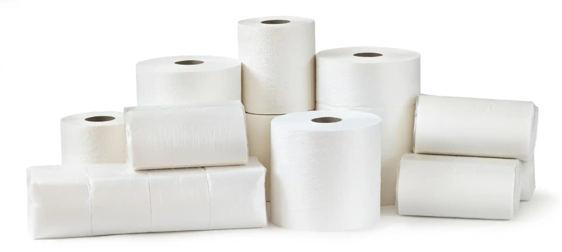 Stacked rolls and packs of white toilet paper and paper towels on a white background