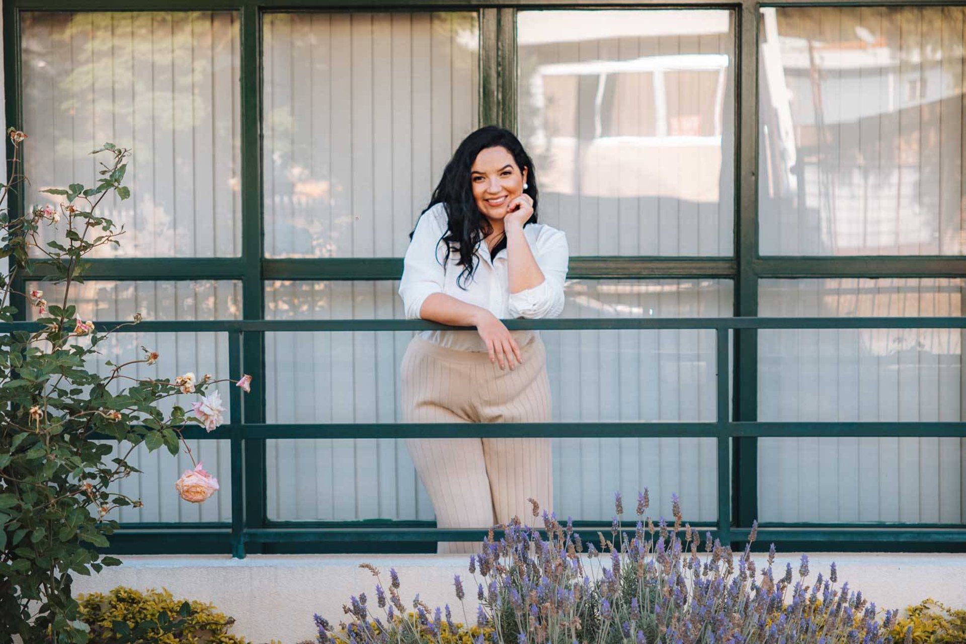 Raabe sorrindo em uma varanda com lavandas e rosas.