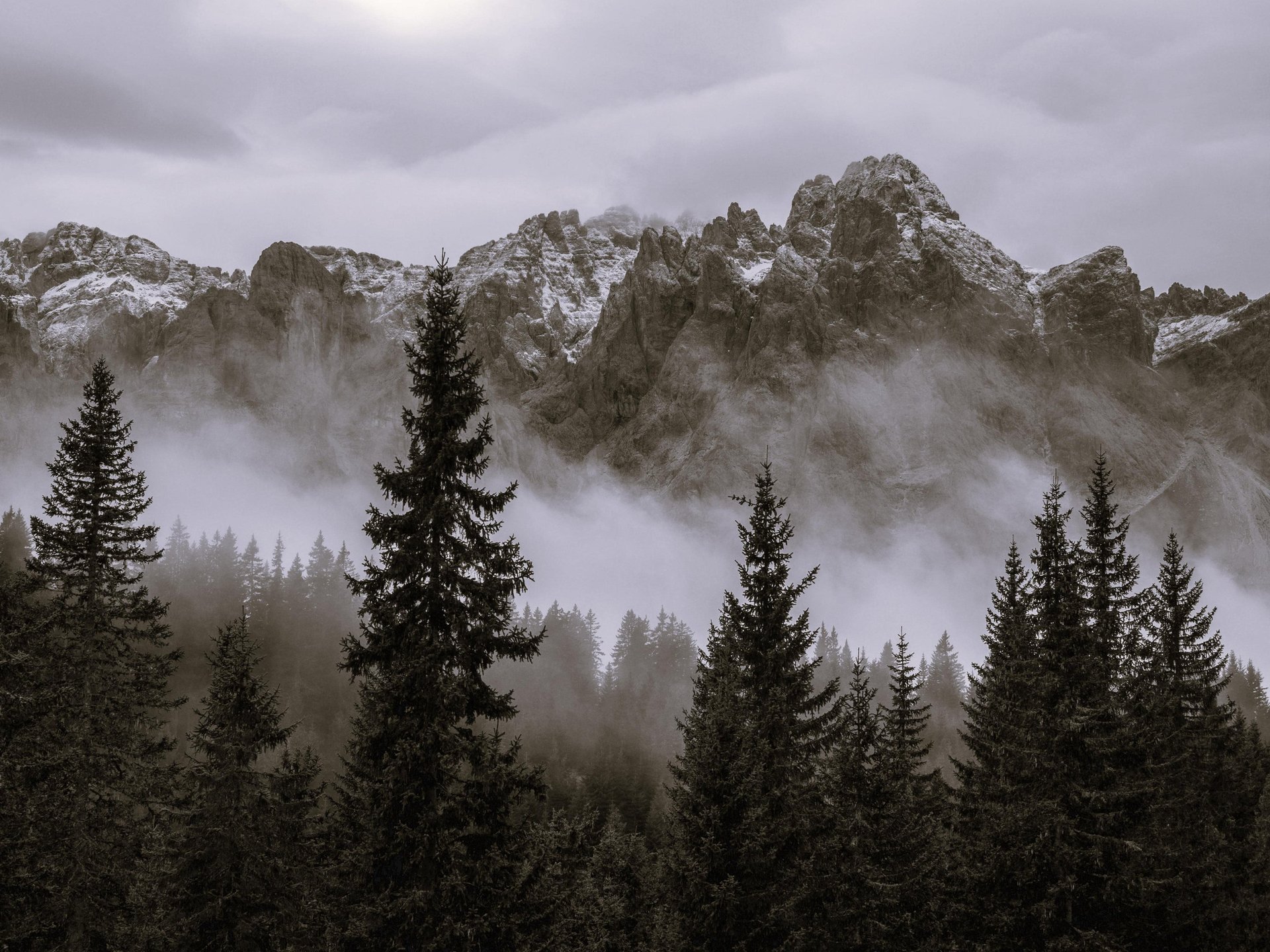 a mountain with clouds and a person standing on top of it
