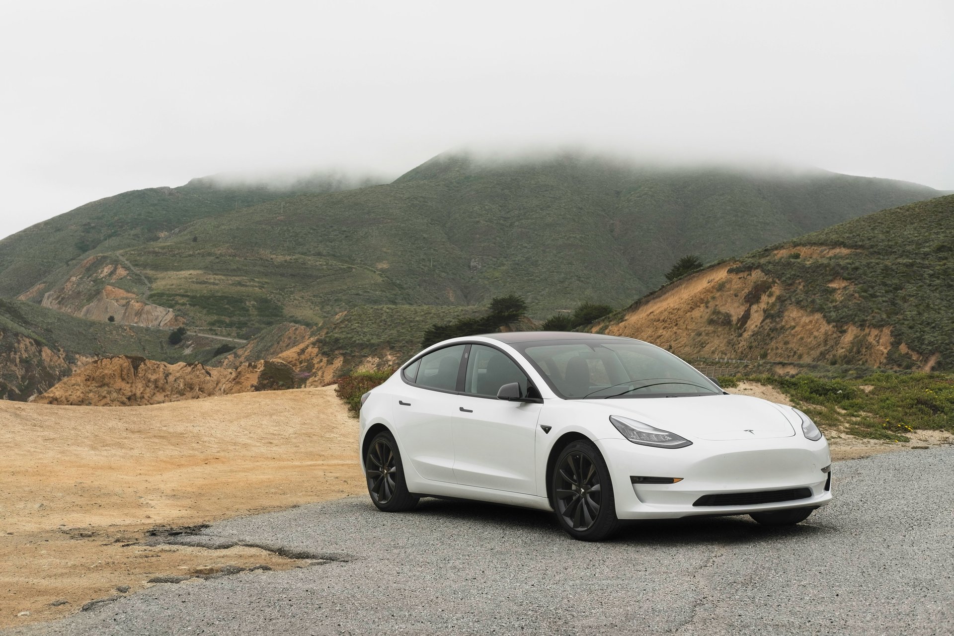 a white car parked in front of a mountain range