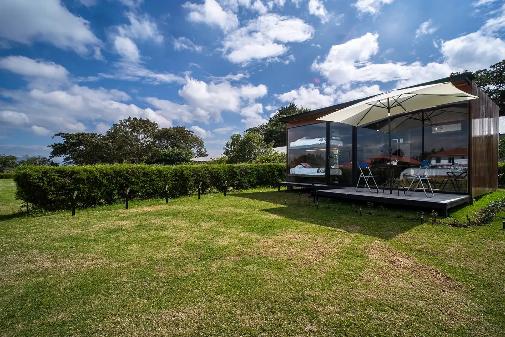 Fotógrafo de airbnb en Quito cabaña bonita con cielo azul en un jardín de cesped y una sombrilla en verano