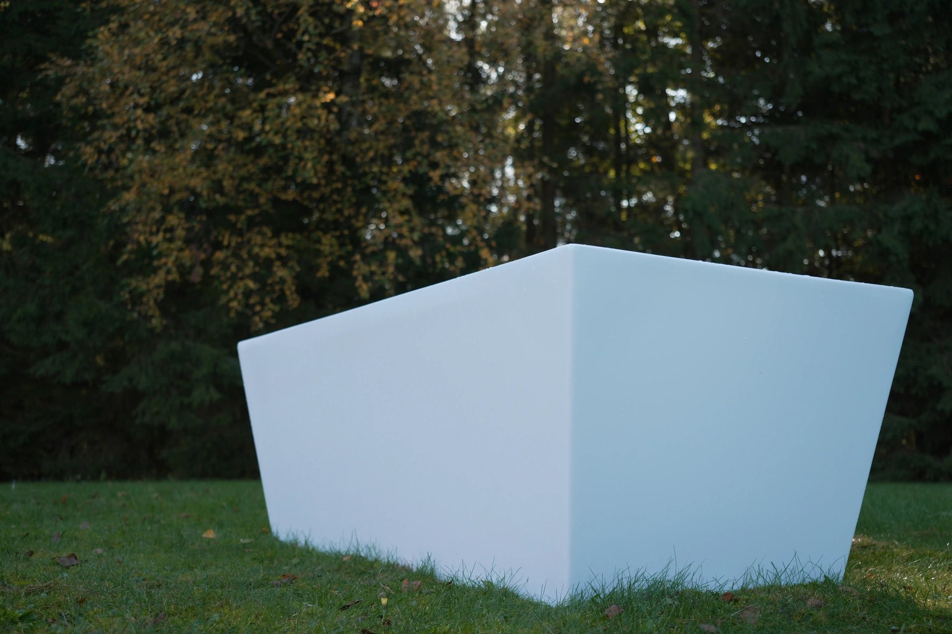 Modern white ColdHug cold plunge tub placed outdoors on grass with forest background