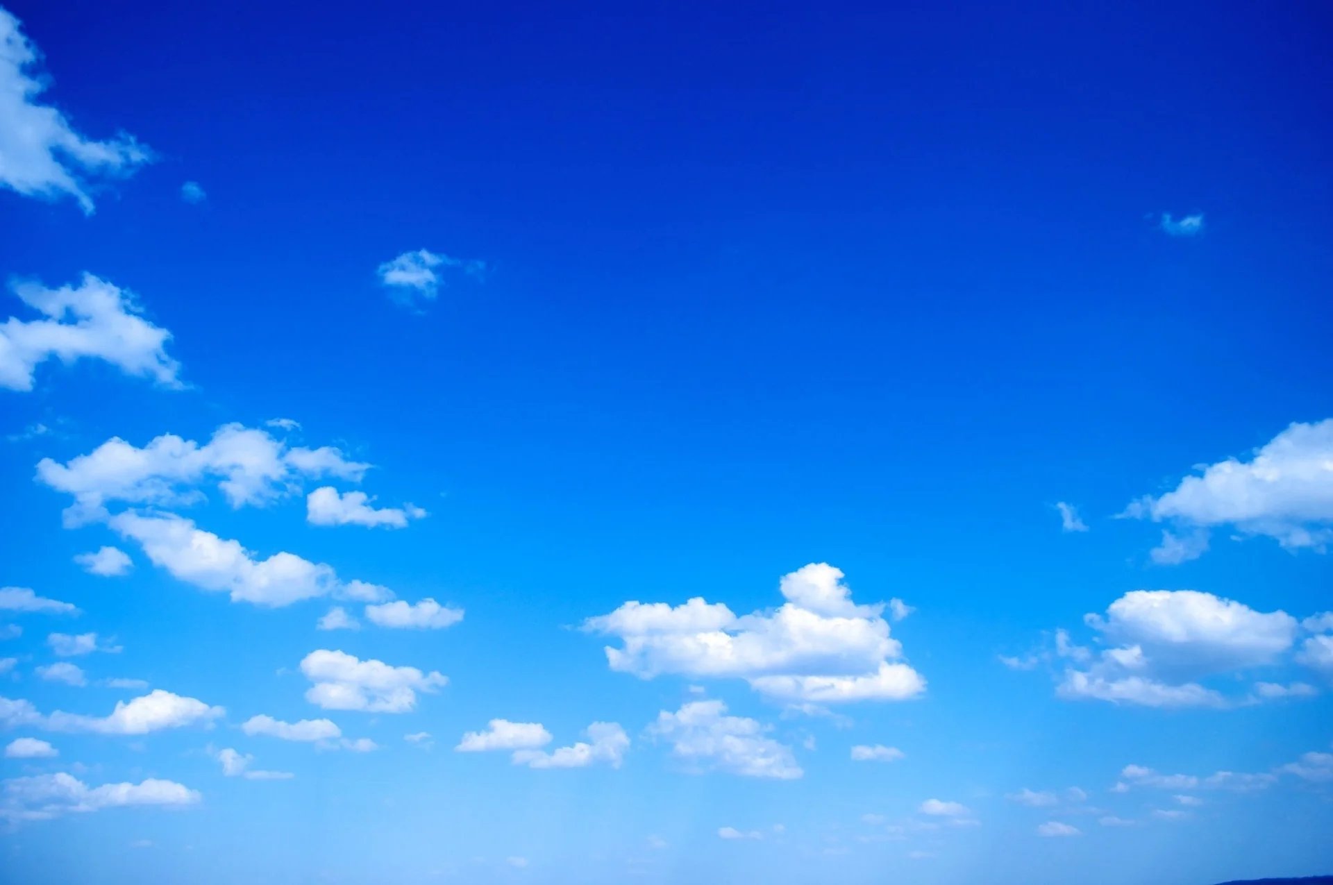 a plane flying through a cloudy blue sky