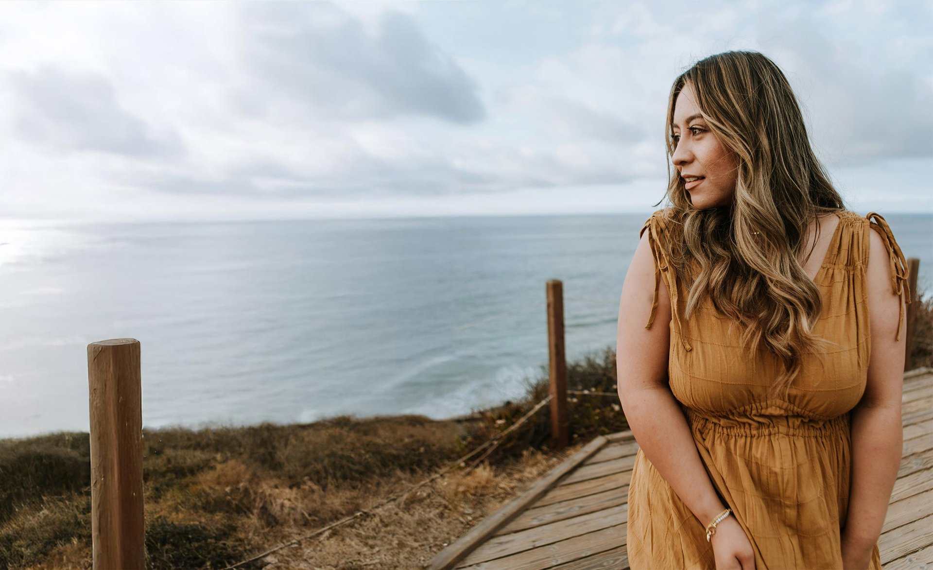 a woman in a brown dress standing on a boardwalk