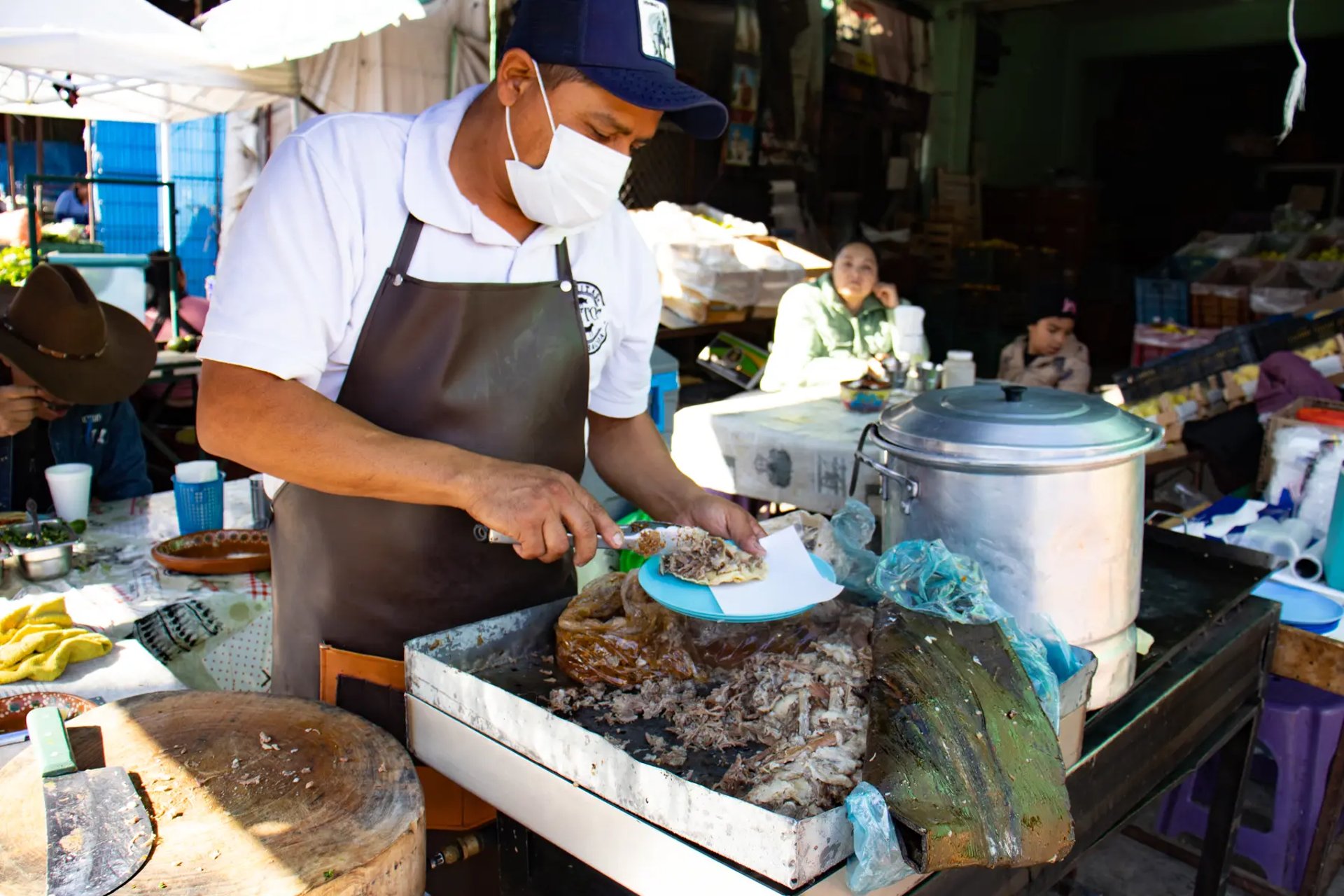 Cocinero preparando barbacoa tradicional en puesto durante servicio en Querétaro.