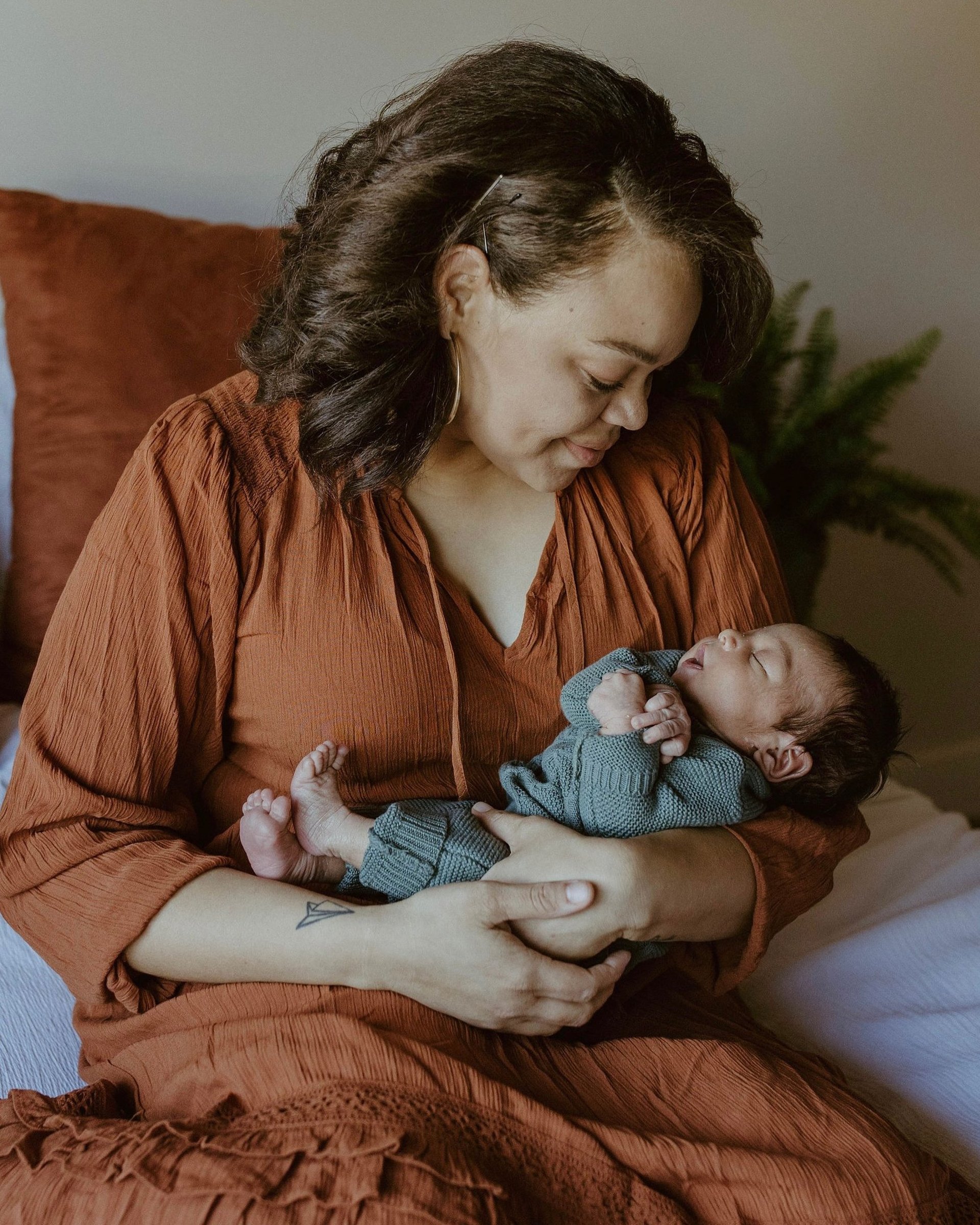 A woman holding a baby in front of a window