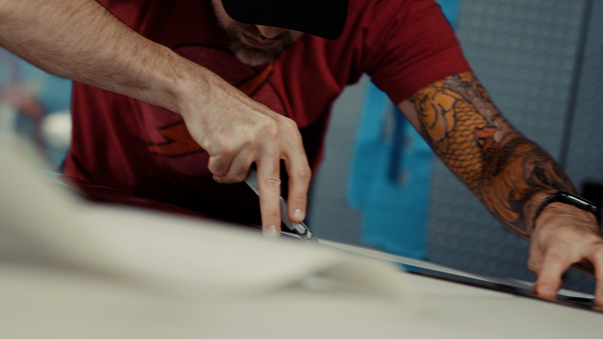 Man leans over a work table with a retractable knife to make a precise cut on car wrapping film