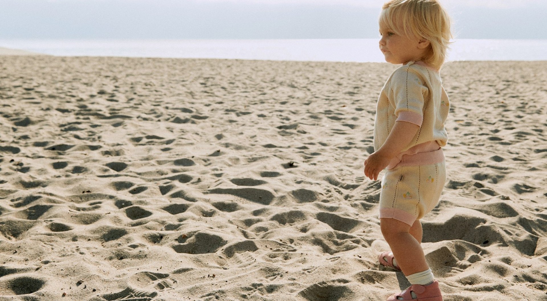 Photo by Wheat of a blond child in a co-ord set on the beach