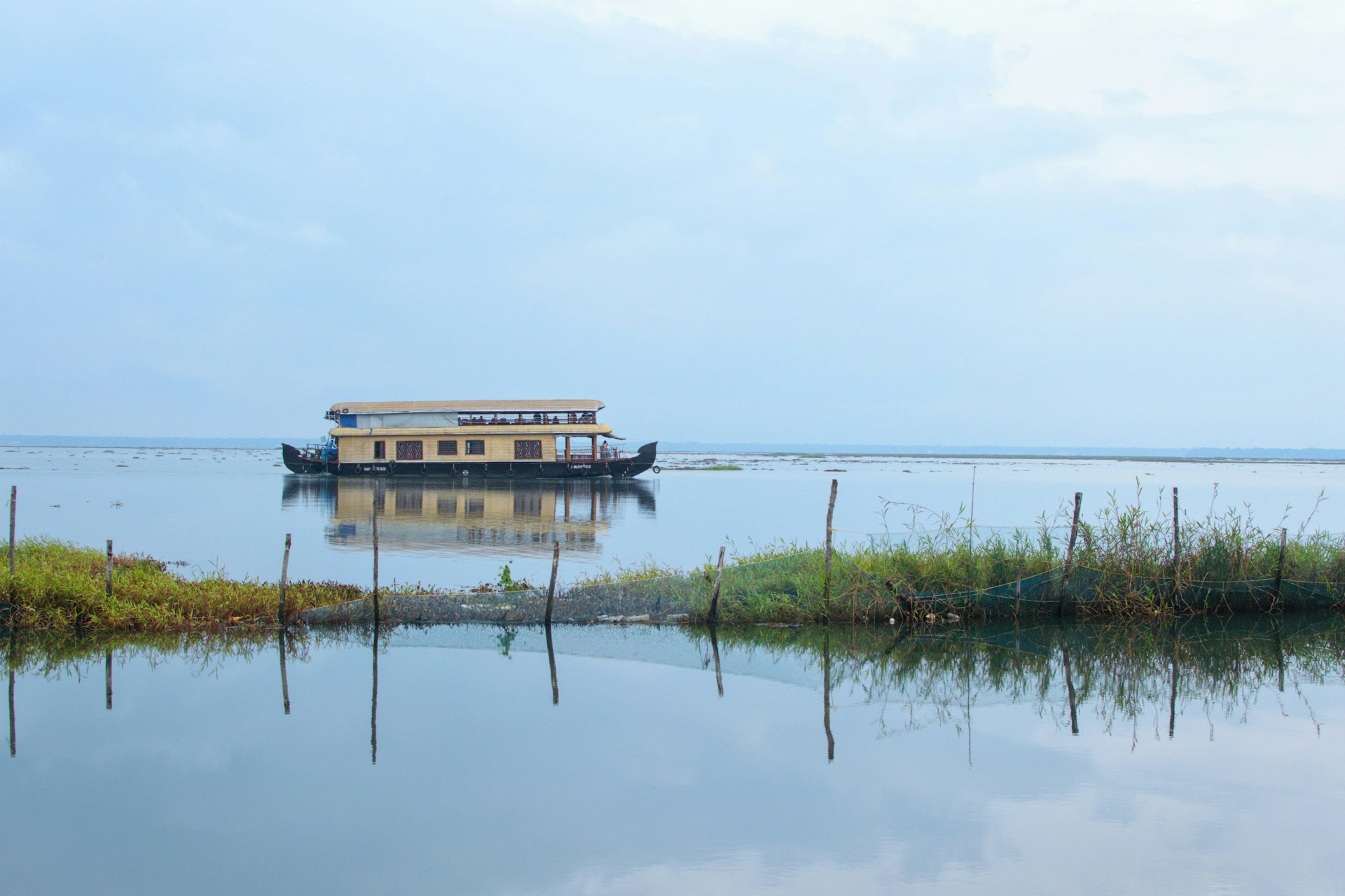 A houseboat cruising through backwaters at Kumarakom Kerala India on a cloudy day.