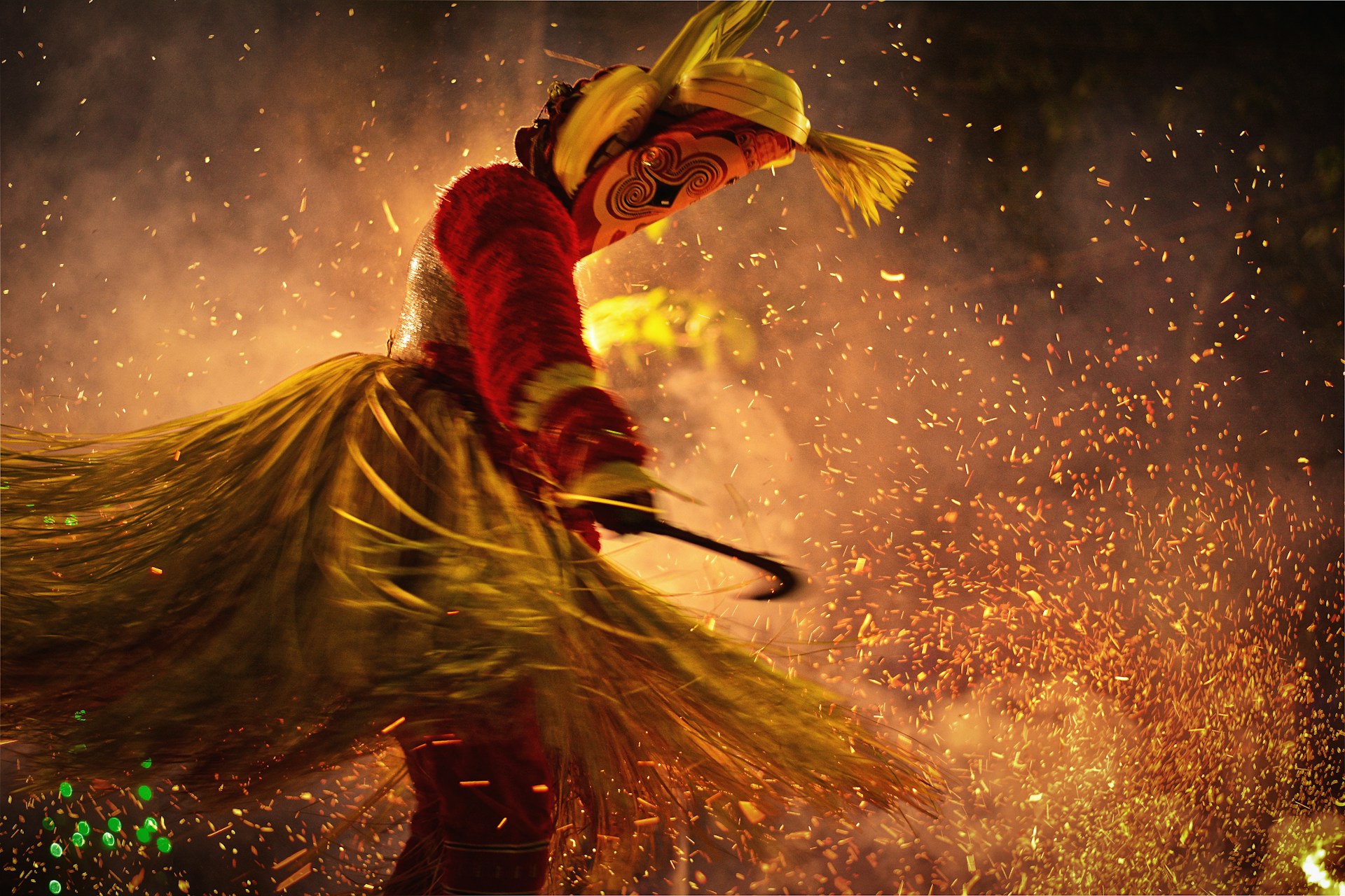 Dancer in traditional Kerala attire performing a ritual dance amidst swirling sparks and smoke, showcasing cultural heritage.
