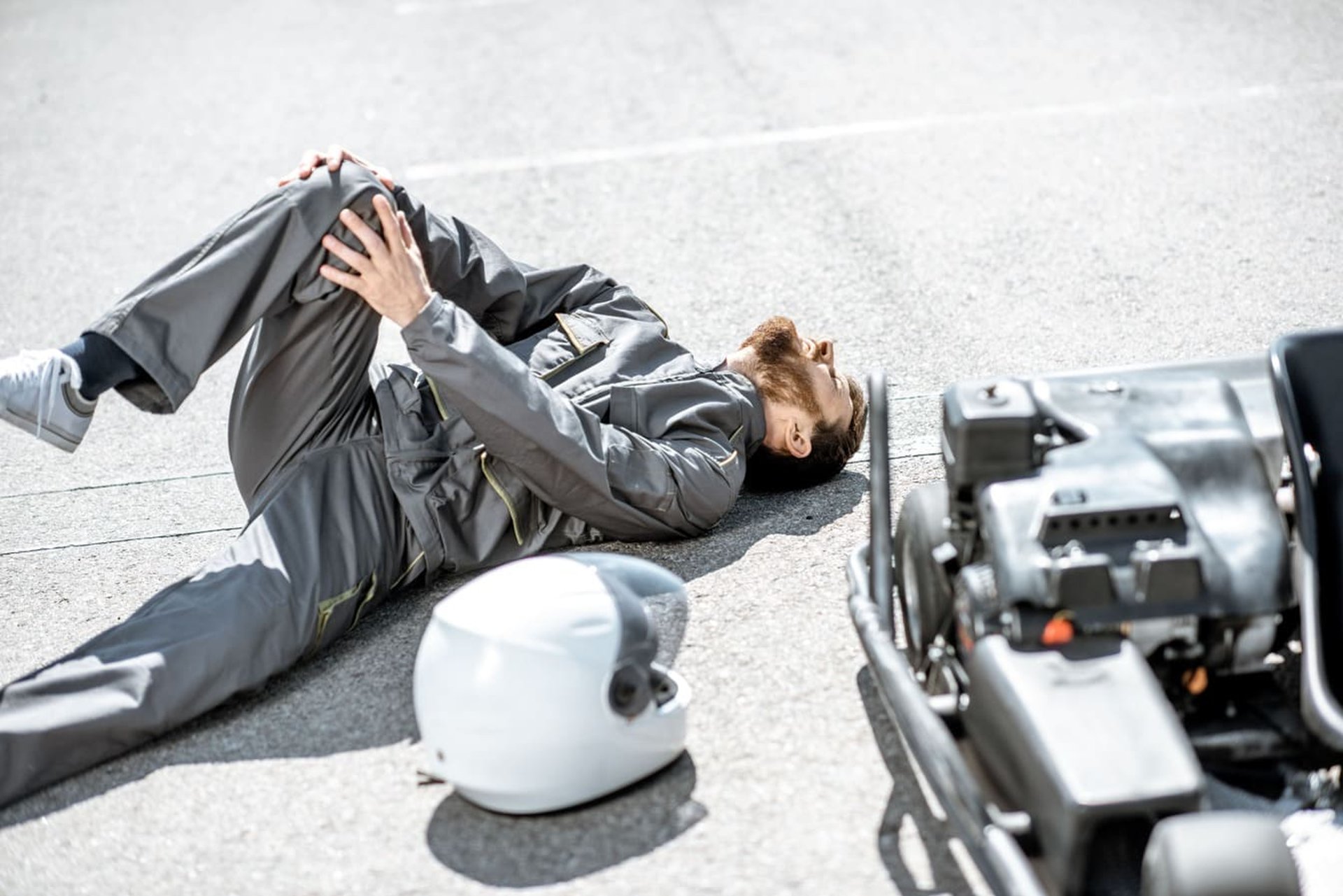 Motorcycle Accidents involving an injured rider lying on the pavement with a helmet nearby and the motorcycle after a crash,