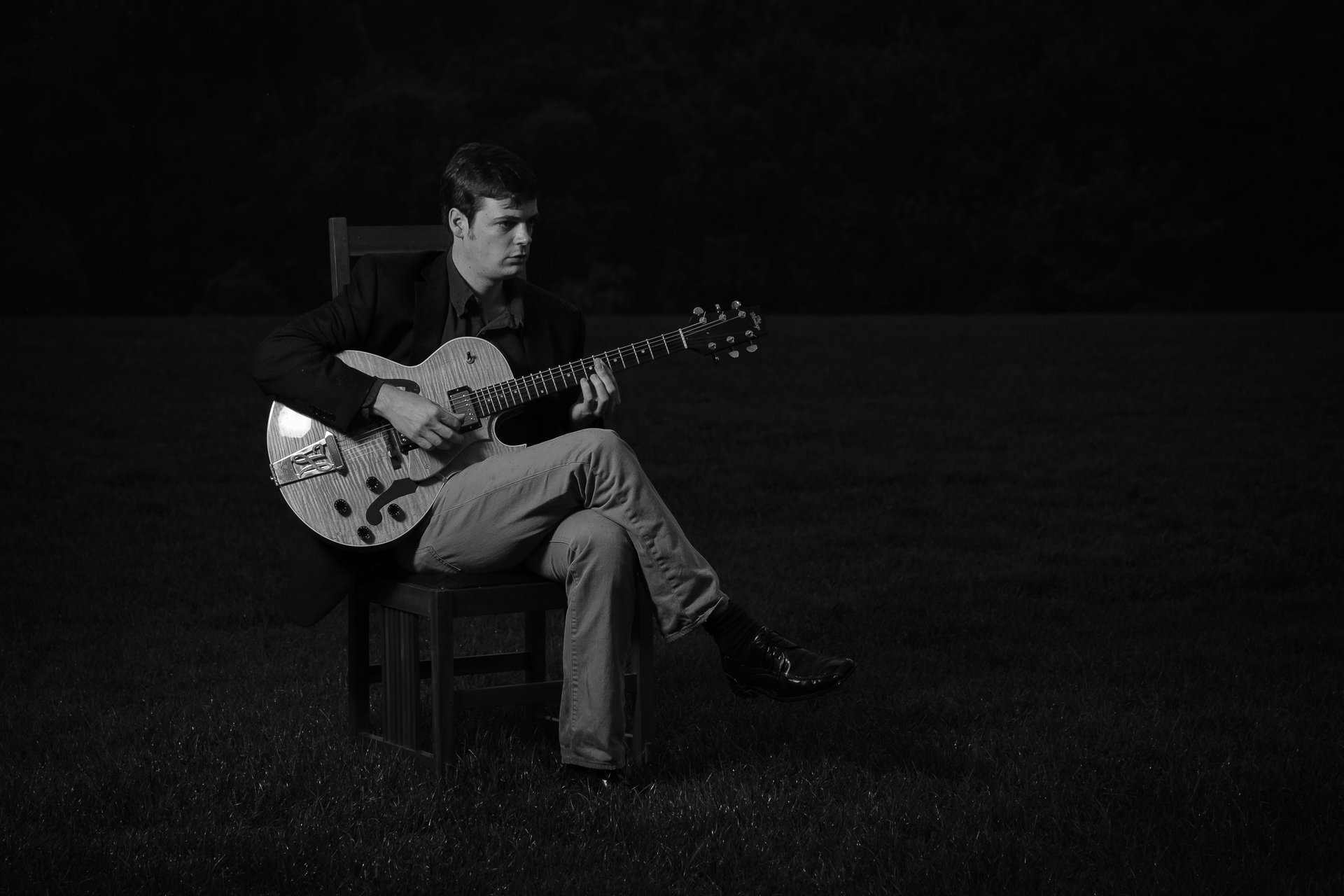 a black and white photo of a man playing guitar