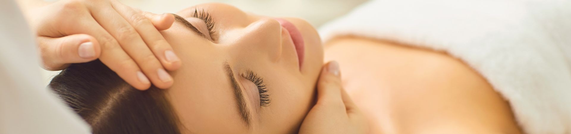 Smiling woman with smooth glowing skin receiving facial treatment.