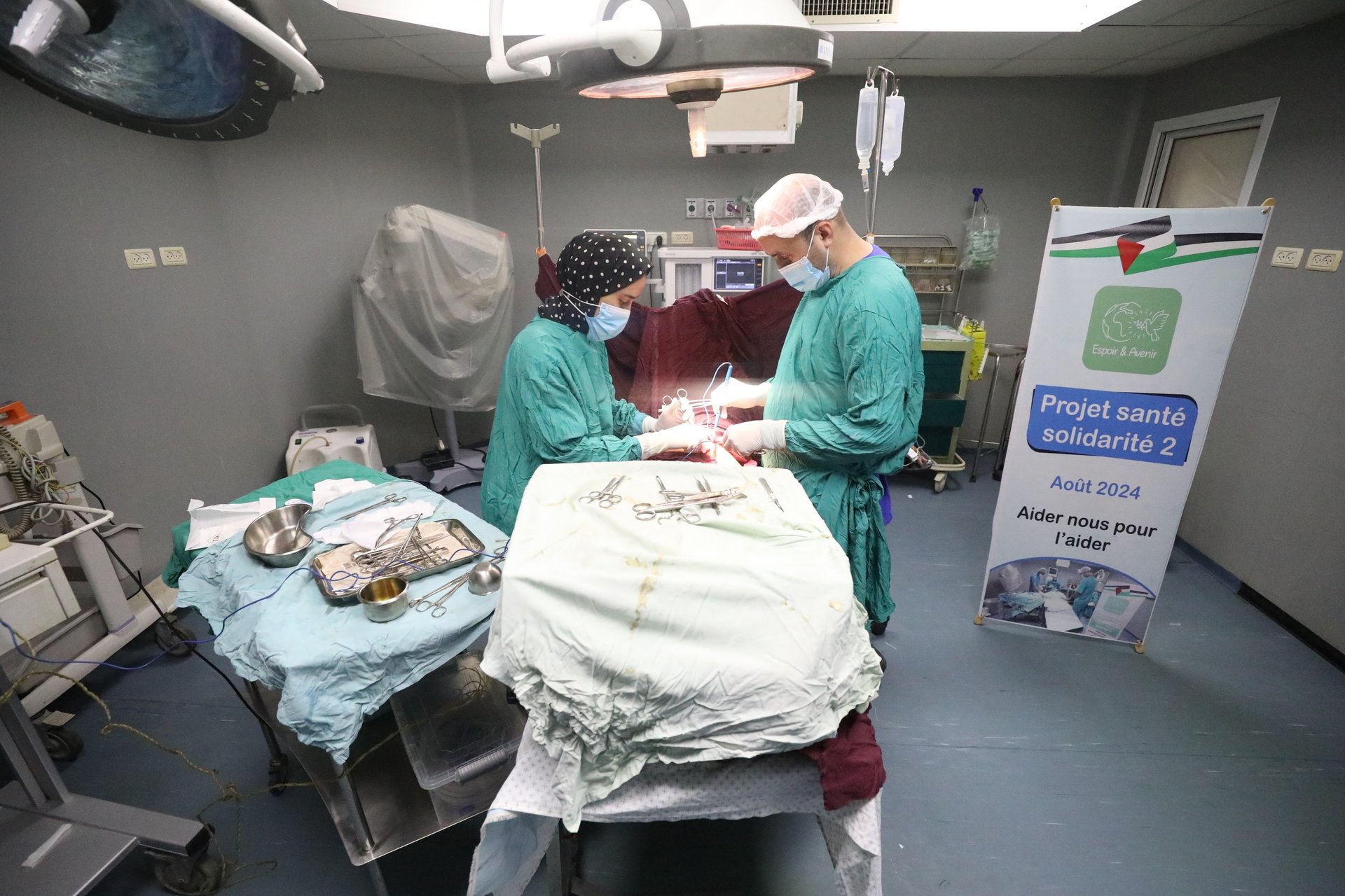 femme réfugiés gaza devant sa tente en train de nettoyer le sol, ses enfants jouent à l'extérieur dans la boue