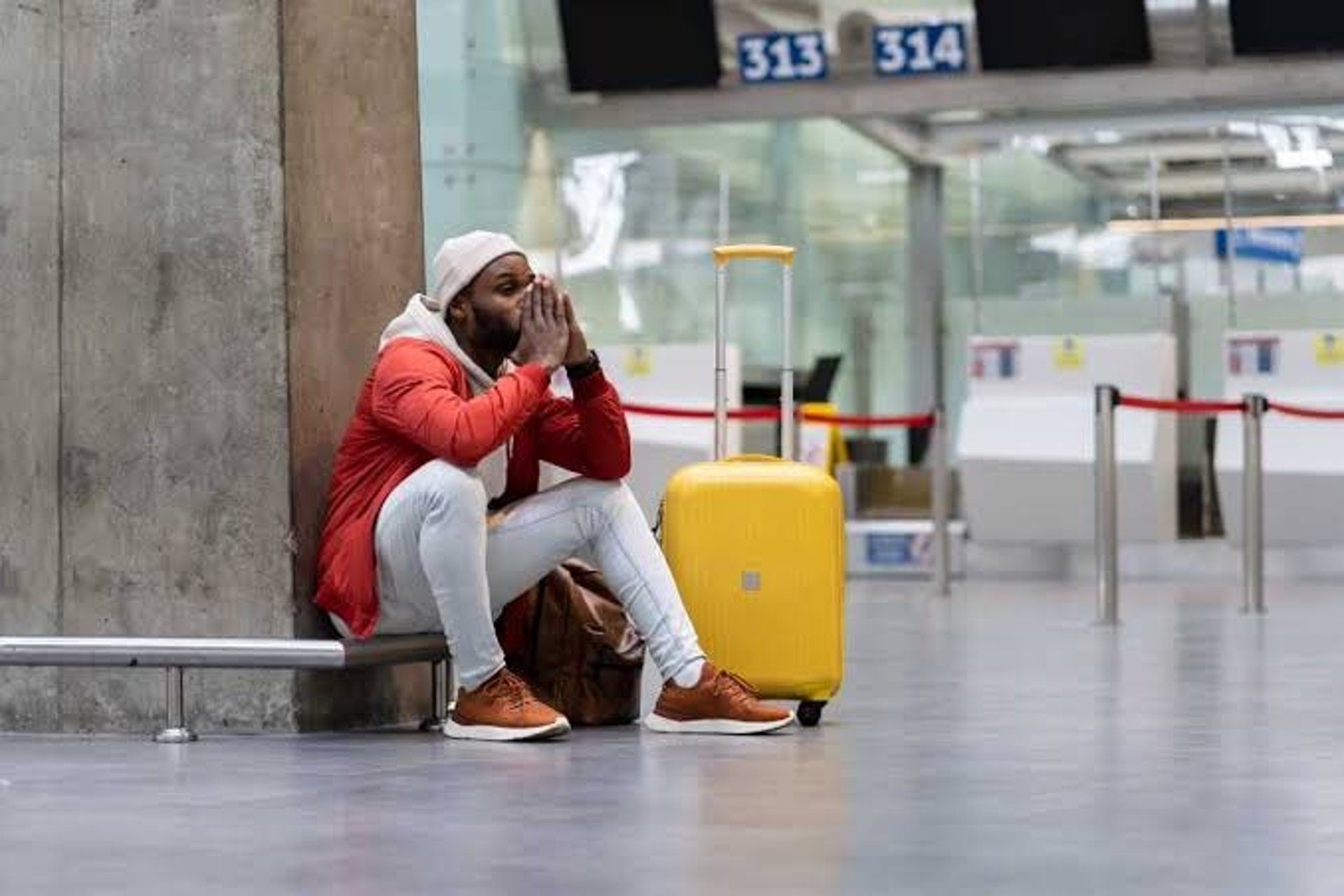 Homem assentado no chão de aeroporto, por ter tido seu vôo cancelado.