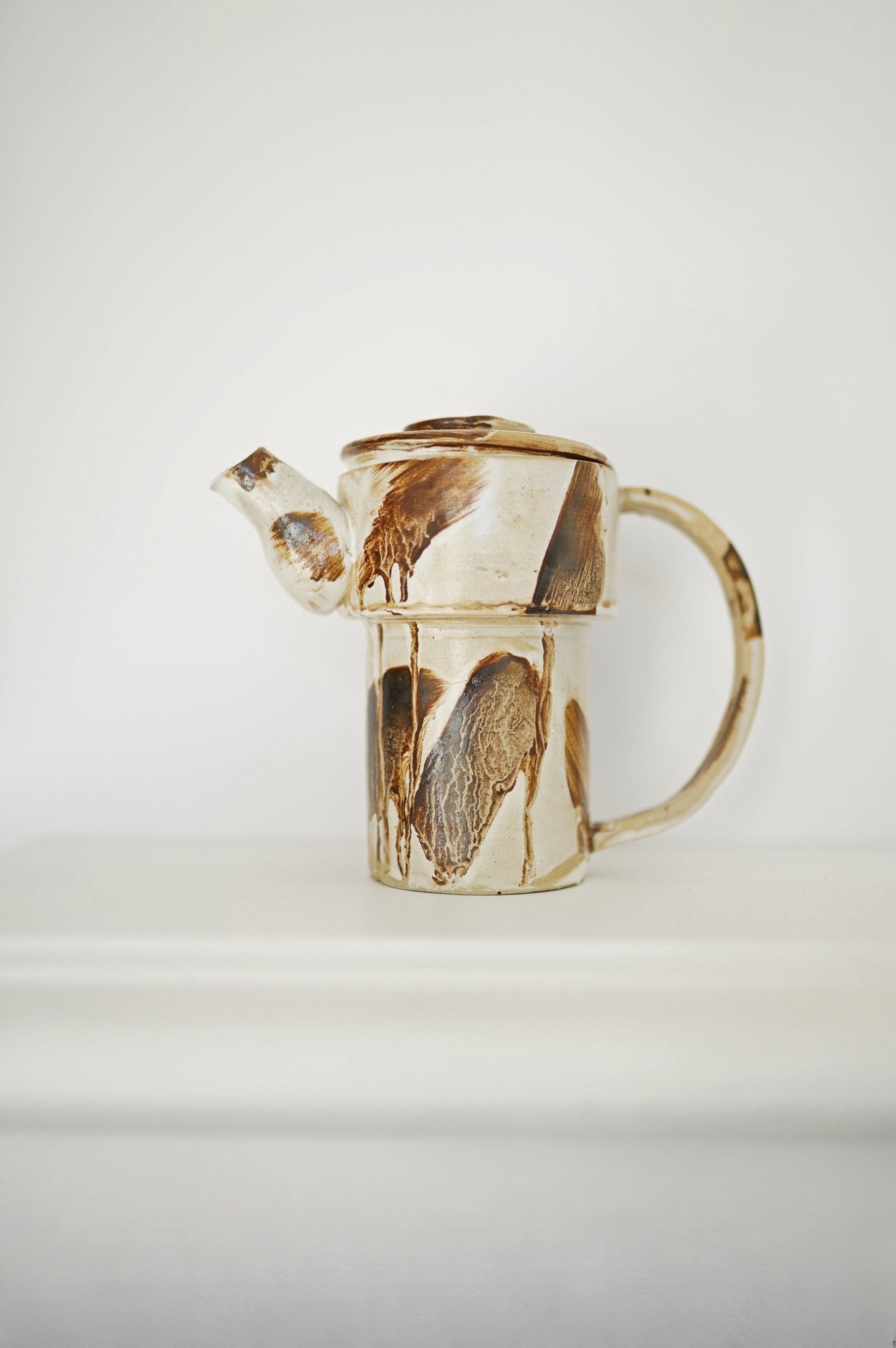 brown clay vase on white wooden shelf