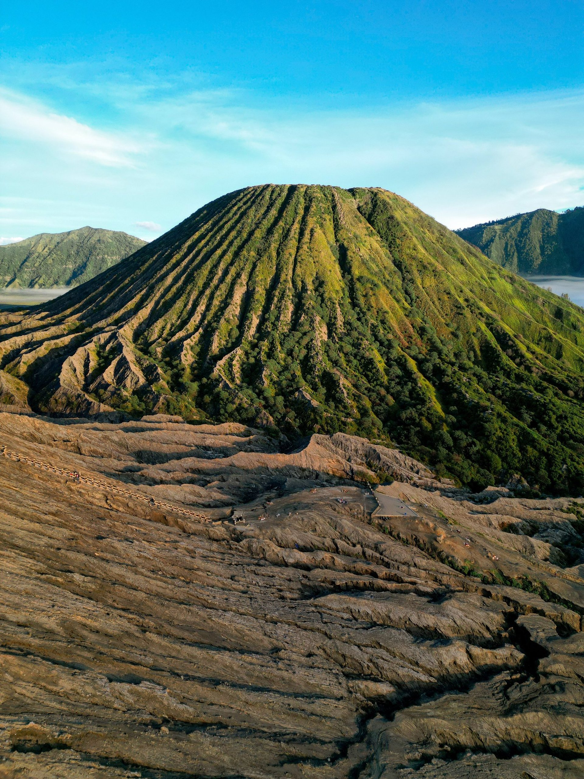 person standing on cliff with volcano background