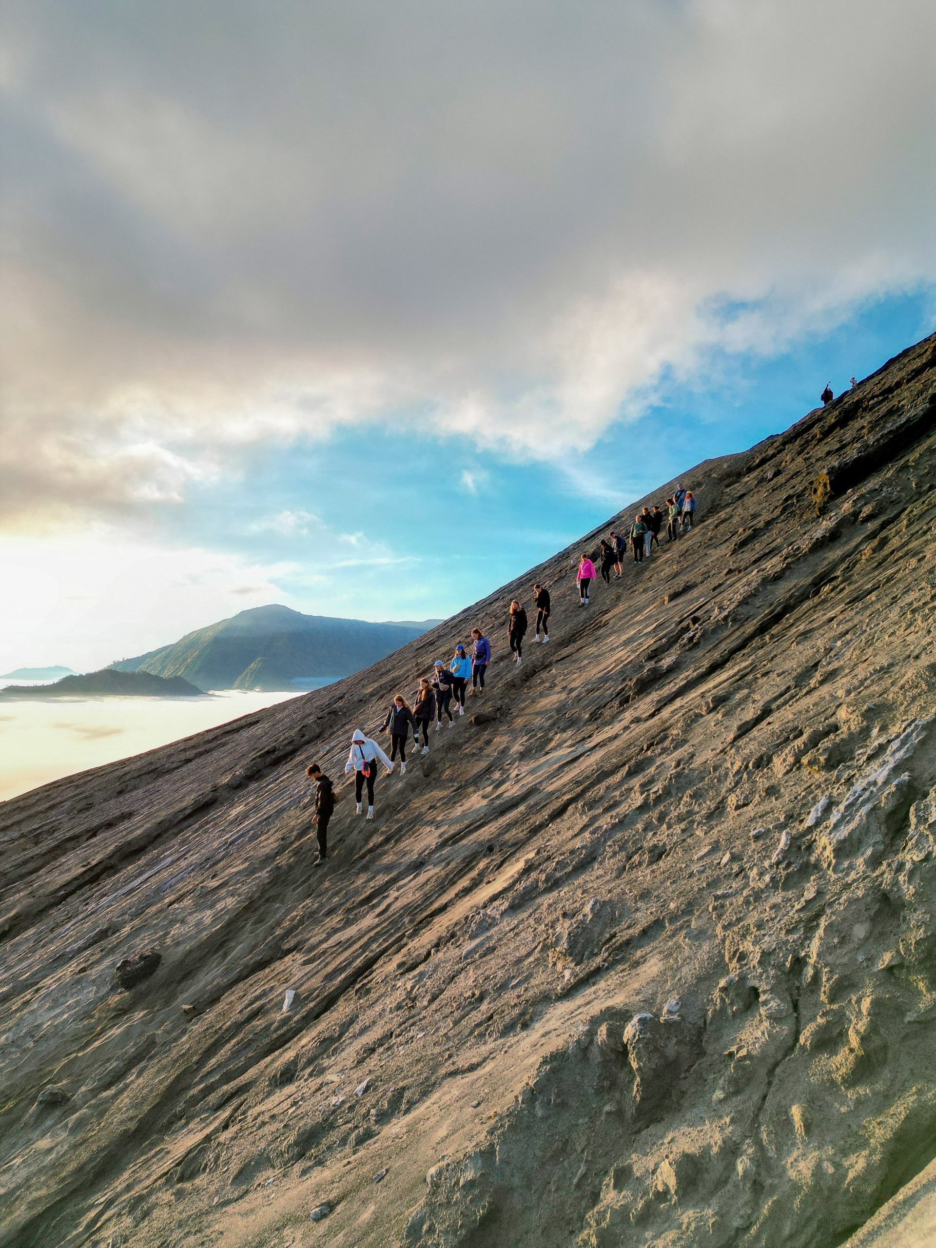 person standing on cliff with volcano background