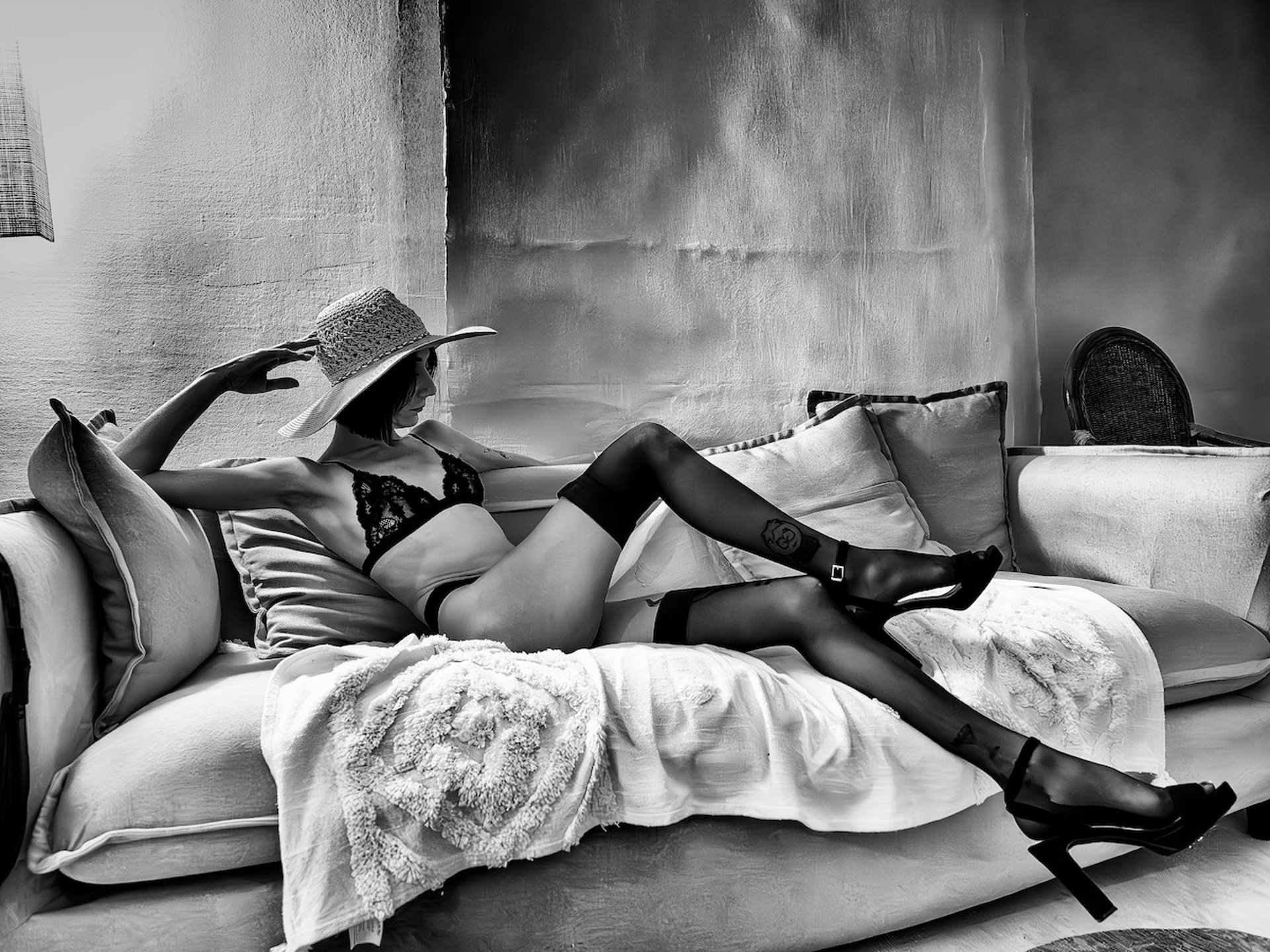 Photo artistique noire et blanc d'une élégante jeune femme en sous vêtements et bas  allongée sur un canapé 