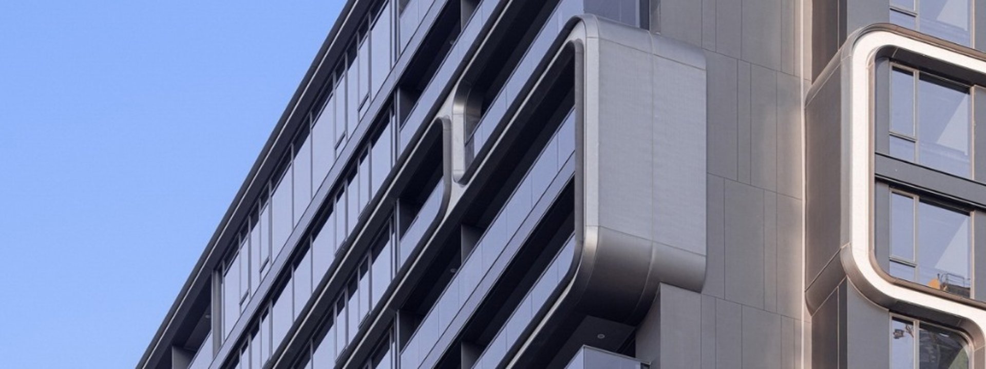 an abstract photo of a curved building with a blue sky in the background