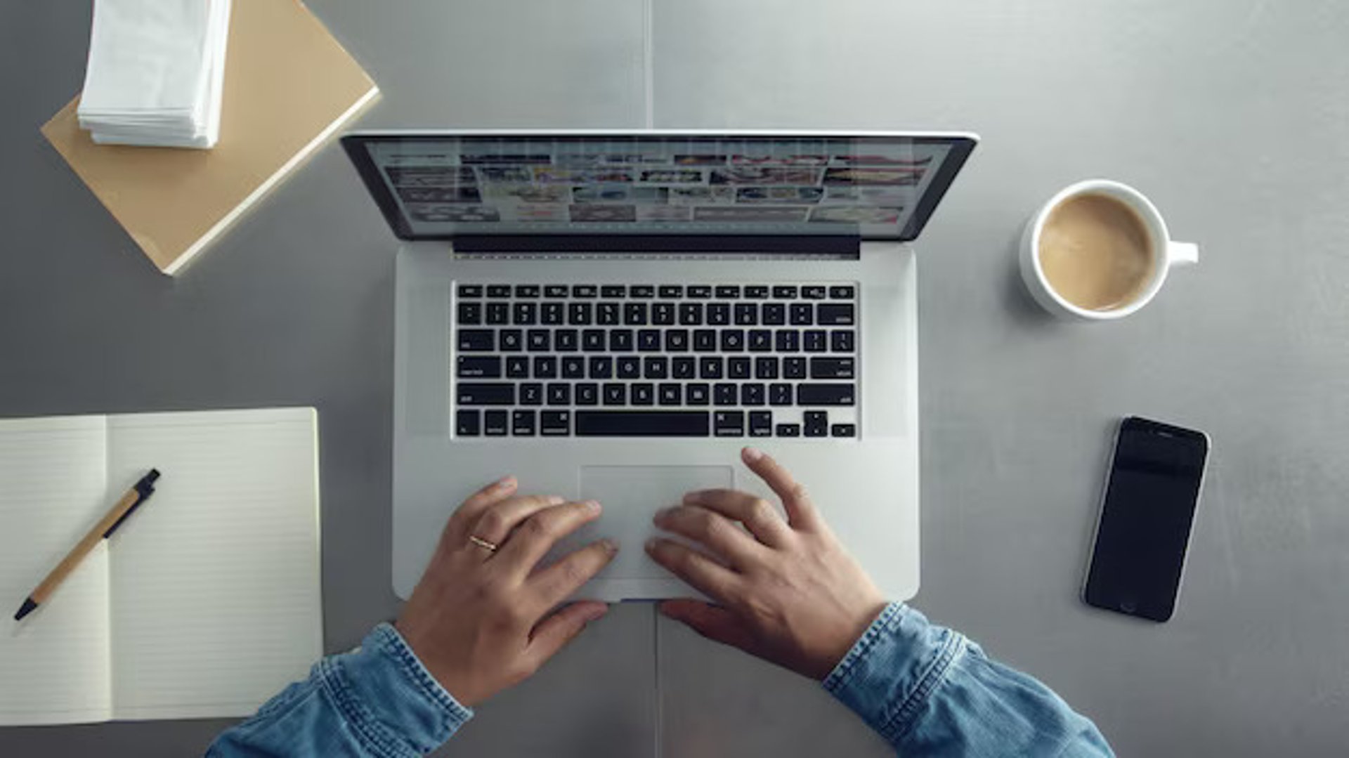 A MacBook with lines of code on its screen on a busy desk