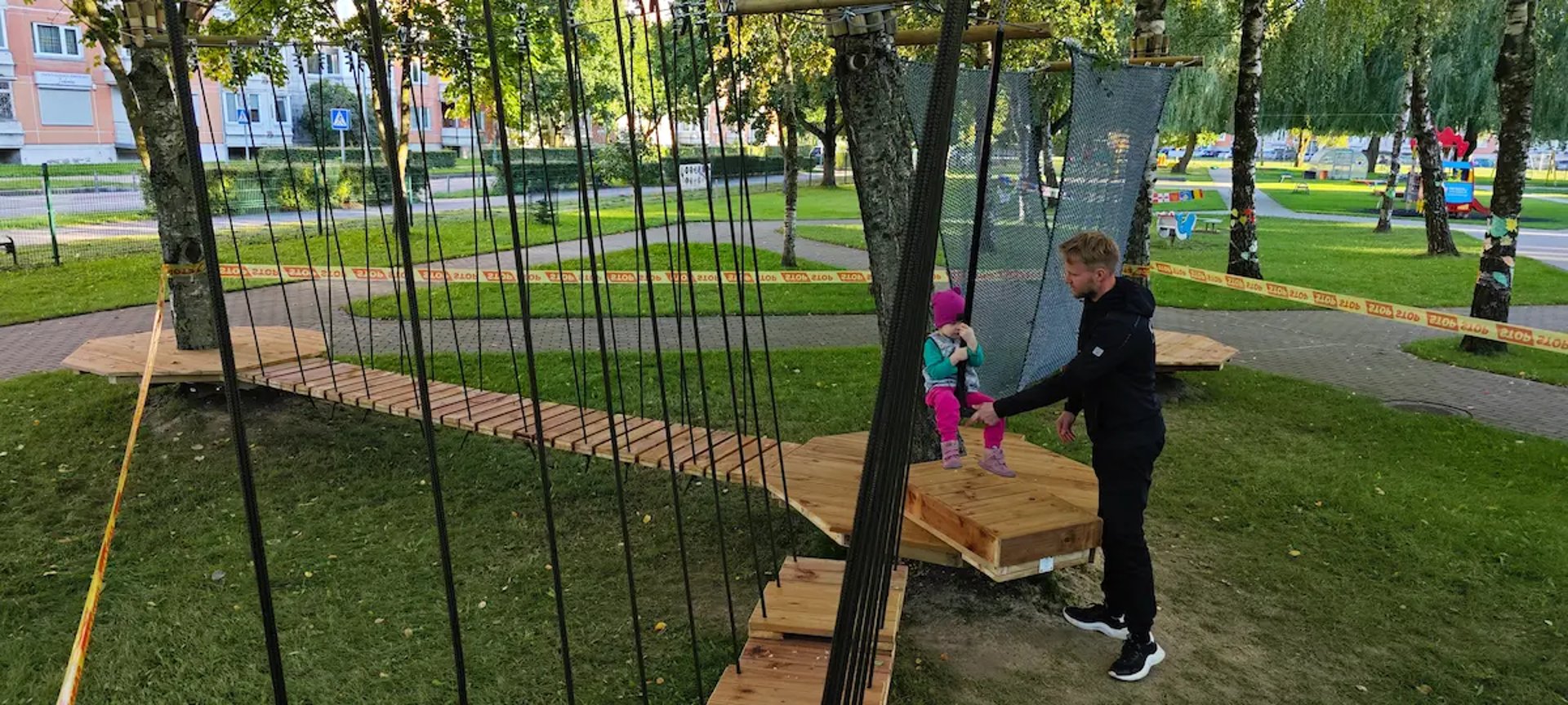 A young boy climbing up a yellow playground structure