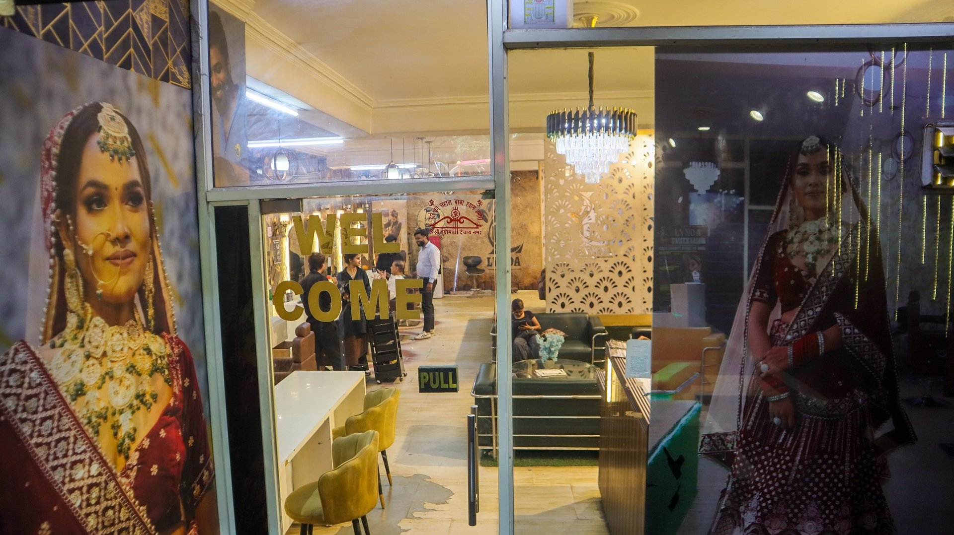 grayscale photo of woman using laptop near three salon chairs