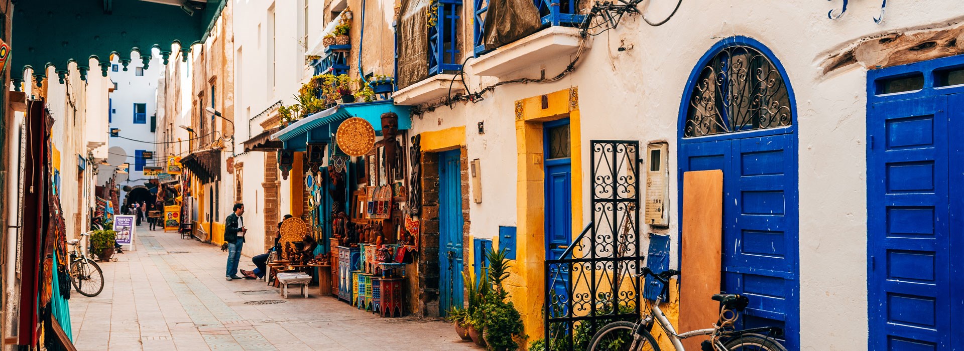 Sun sets over the ocean with boats and a fortress.