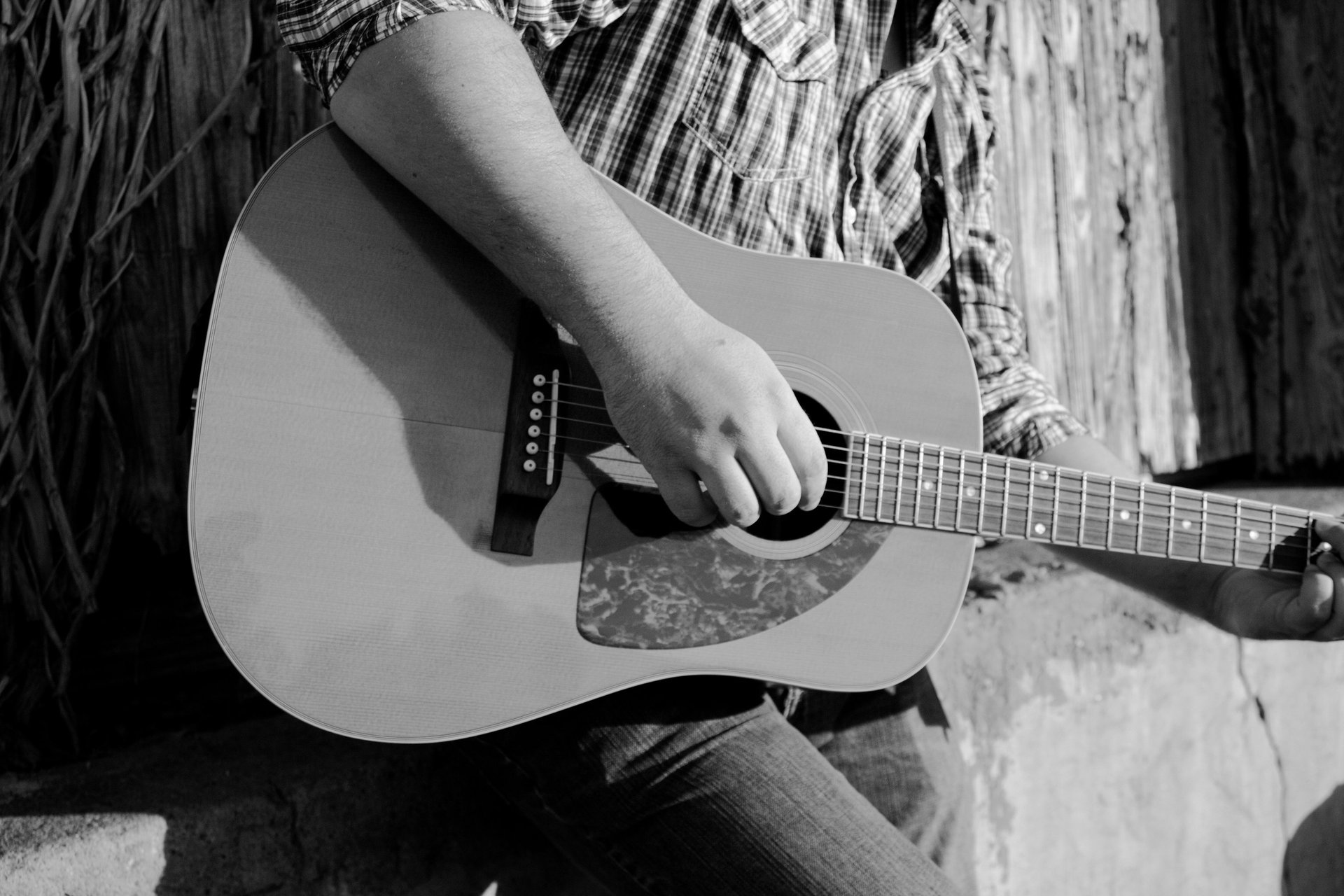 greyscale photography of person playing acoustic guitar