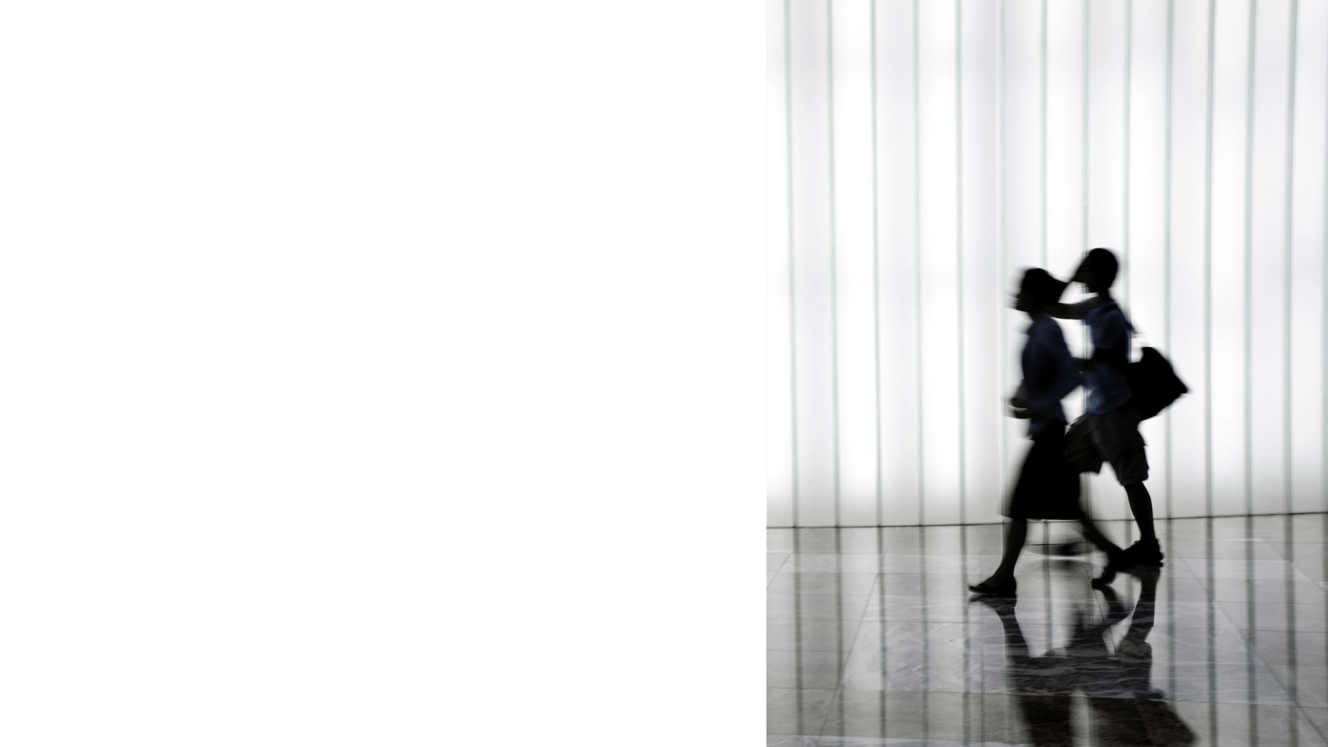 A diffuse image of a busines swoman and man appearing to walk fast in a corridor