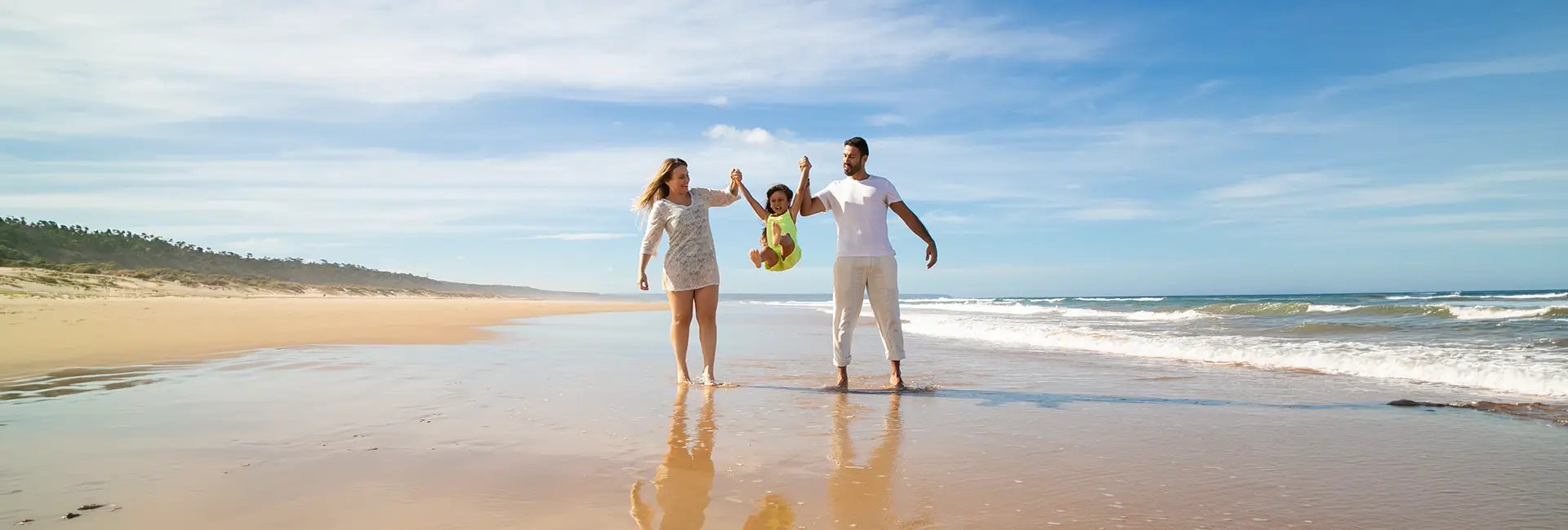 man, woman and child holding hands on seashore