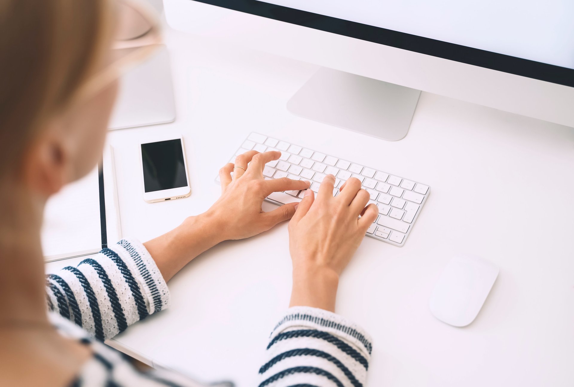 a woman sitting at a desk with a keyboard and mouse