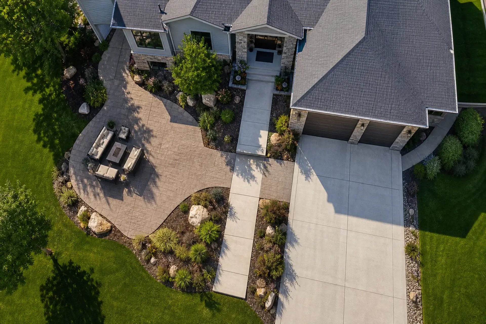 suburban backyard in Utah, large stamped concrete patio connected by a clean concrete walkway to a two-car concrete driveway