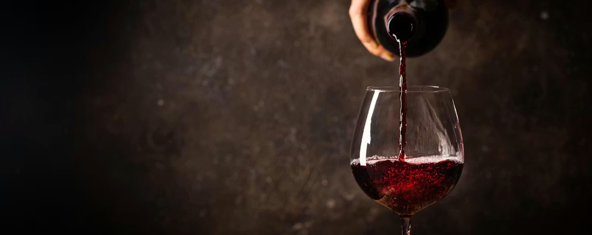 a person pours wine into a wine glass