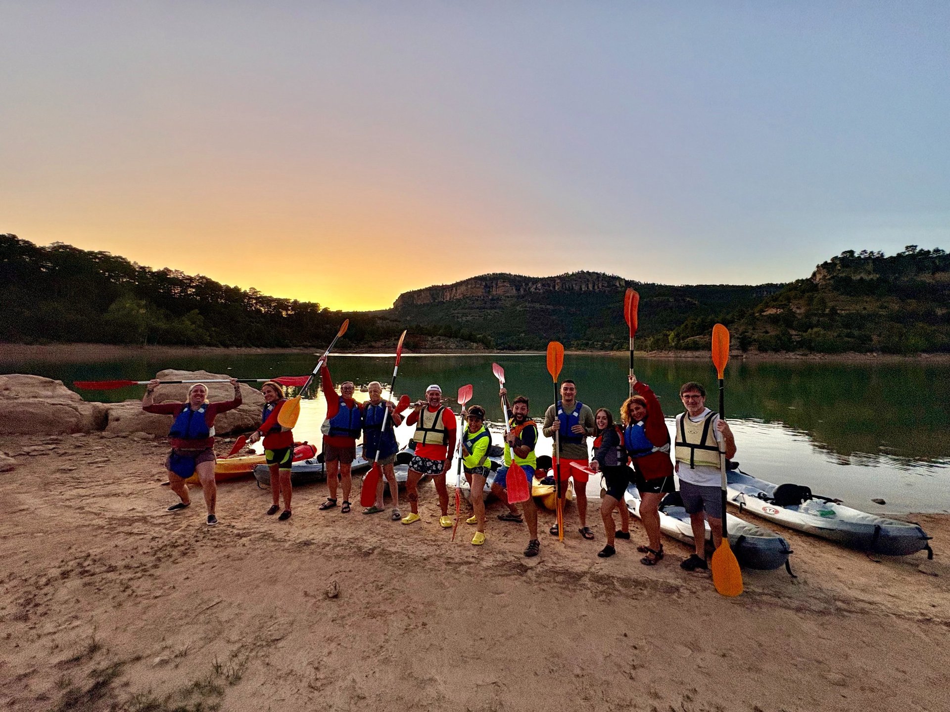 Grupo de piraguistas en el embalse de la Toba con grandes paredes a lo lejos y la puesta de sol en la Serranía de Cuenca