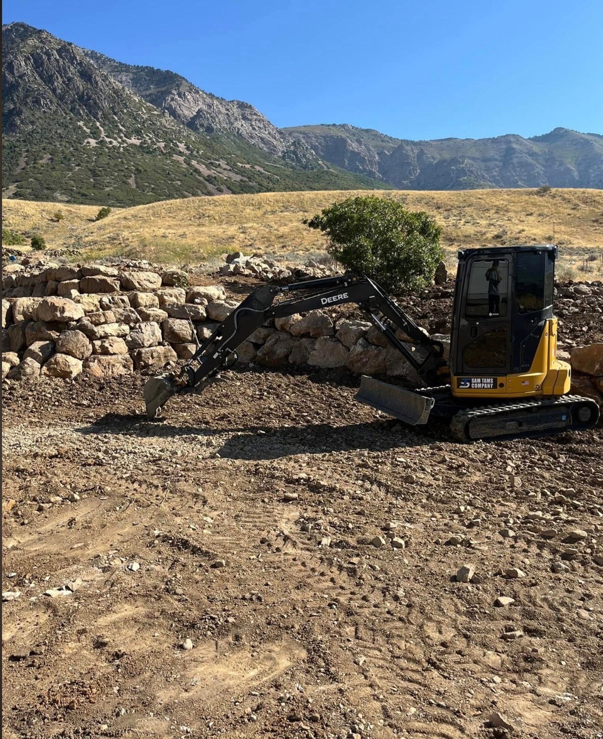 CAT excavator next to finished boulder wall