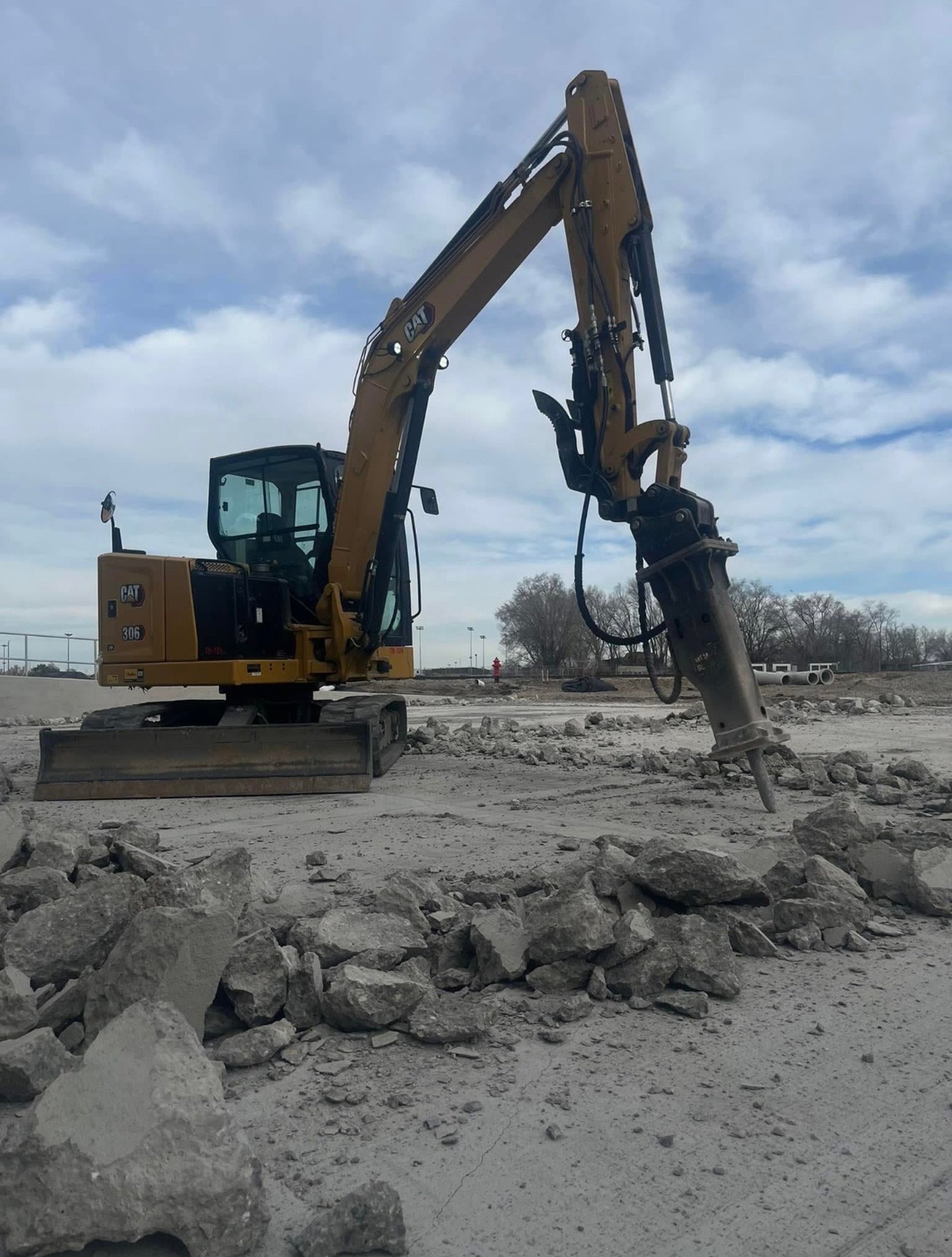 Mini excavator jackhammering concrete 