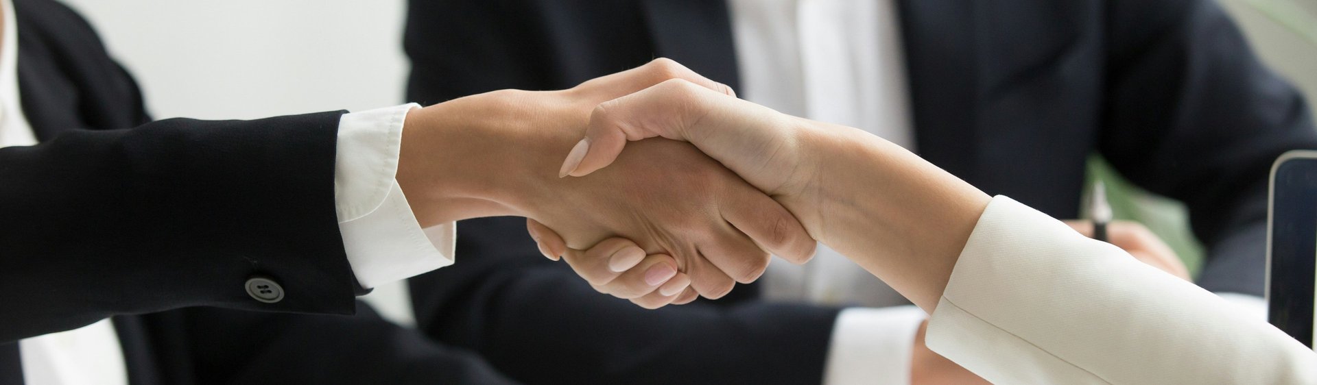 two people shaking hands in front of a laptop