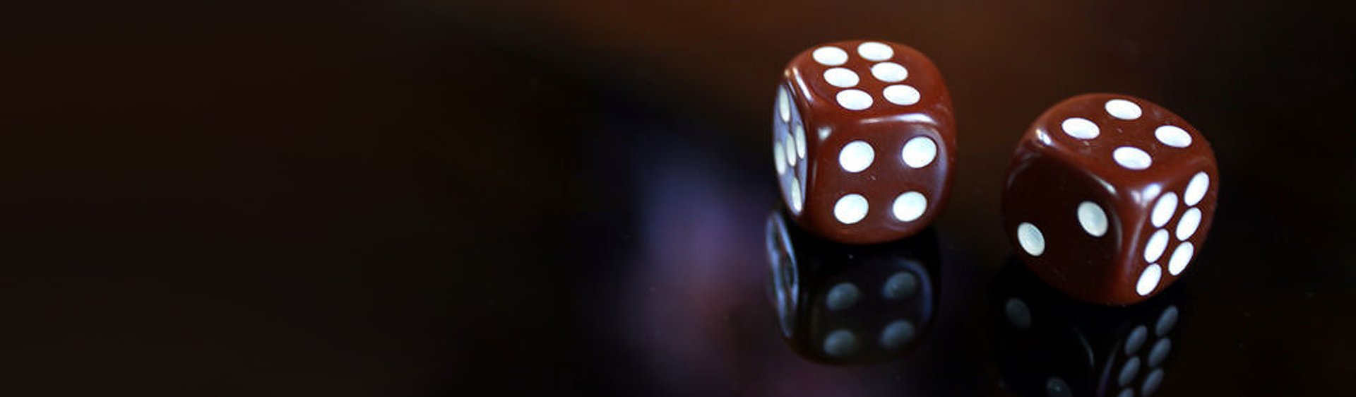 Photo shows two dark red dices on a dark surface