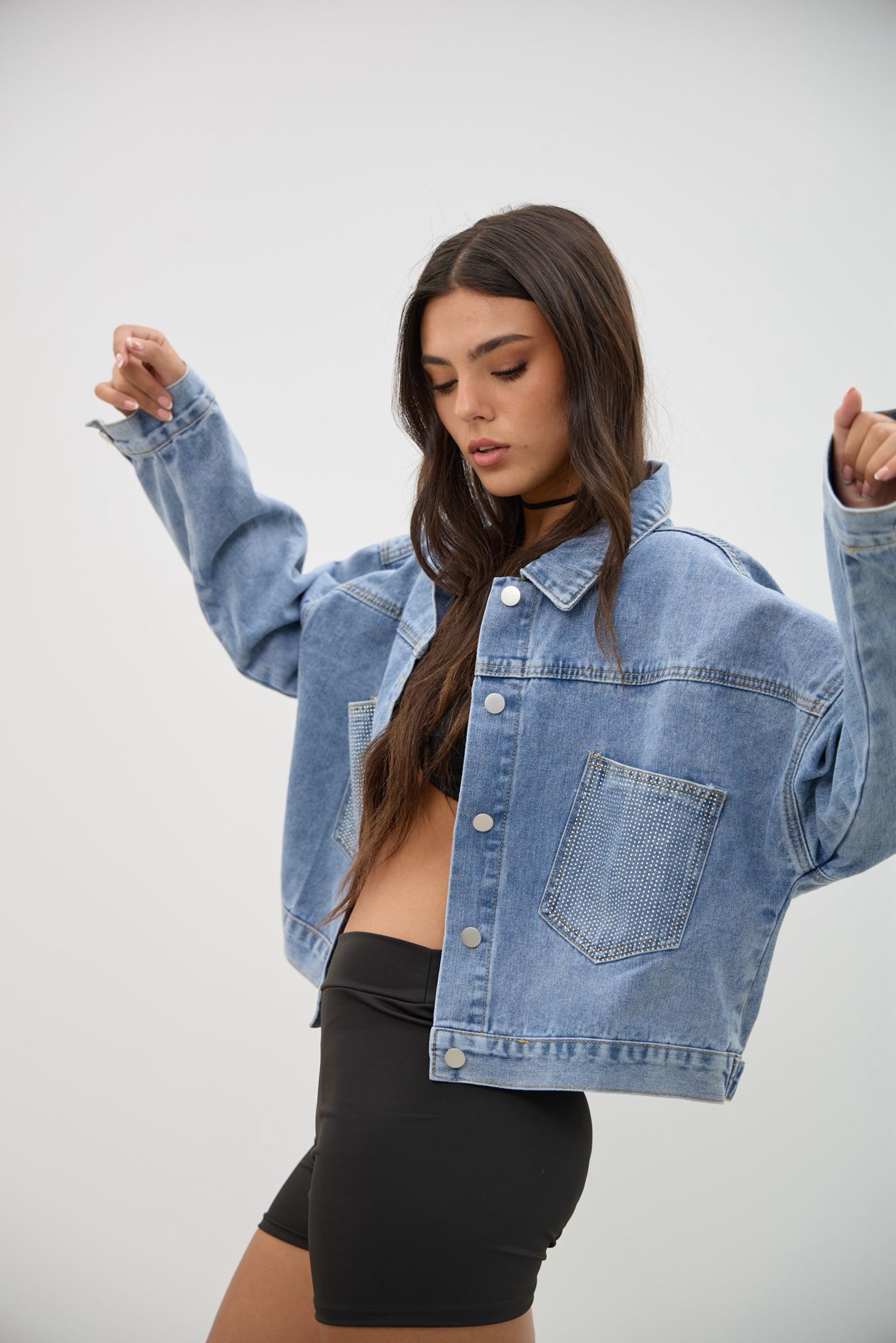 woman in black long sleeve shirt and blue denim jeans sitting on white concrete wall