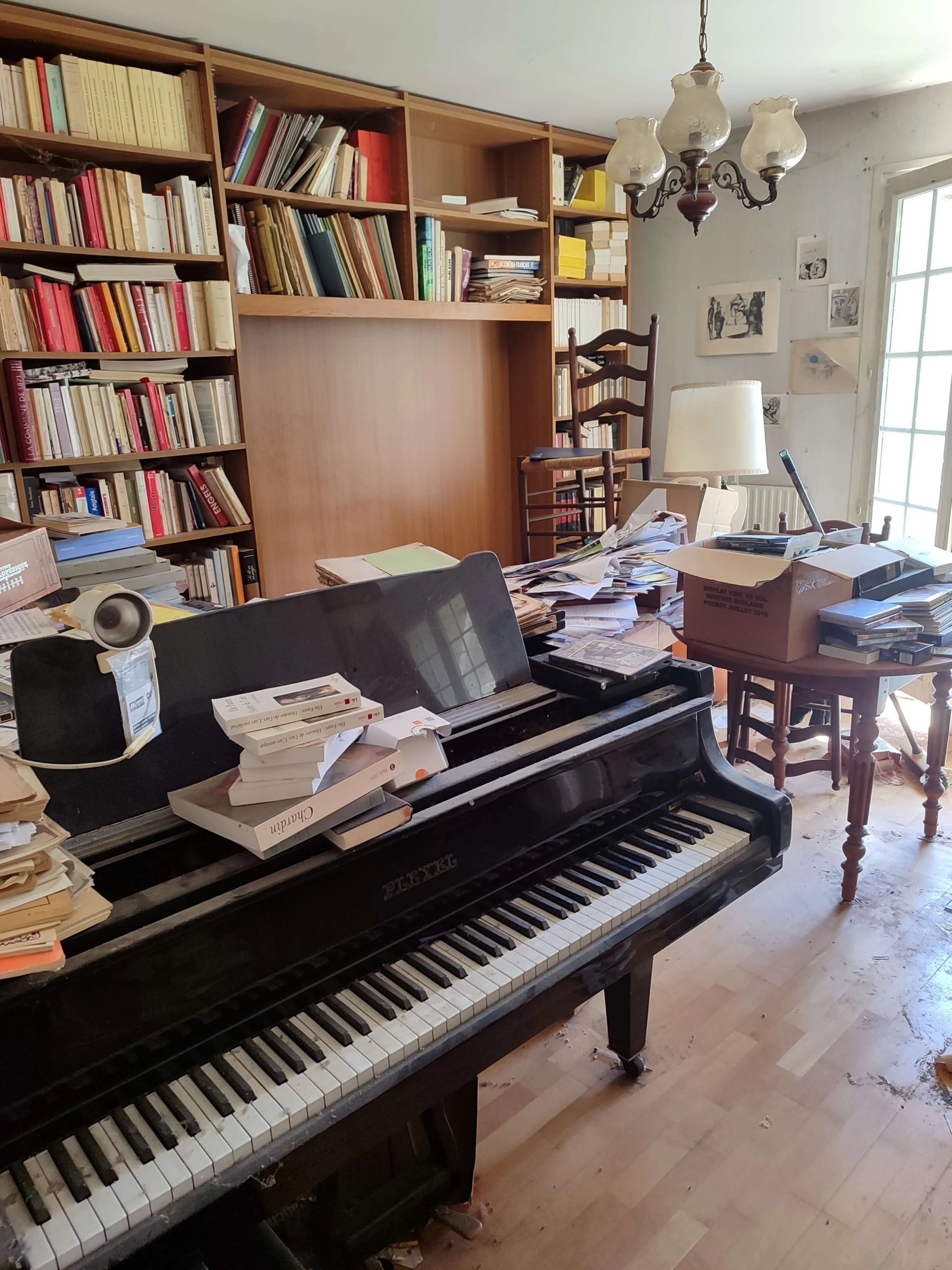 Débarras Lepeltier - Un piano noir élégant placé dans une pièce lumineuse avec des murs clairs et un sol en bois.