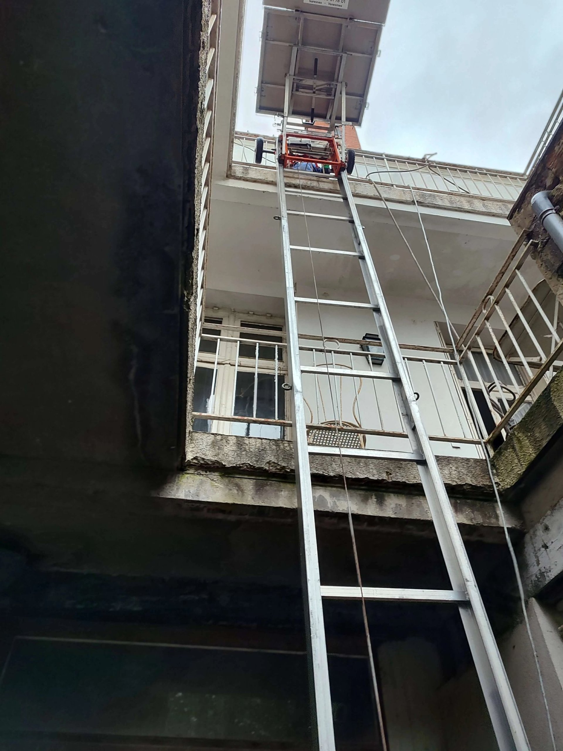 Monte-meuble Lepeltier - Chargement de meubles dans un espace étroit à ciel ouvert.