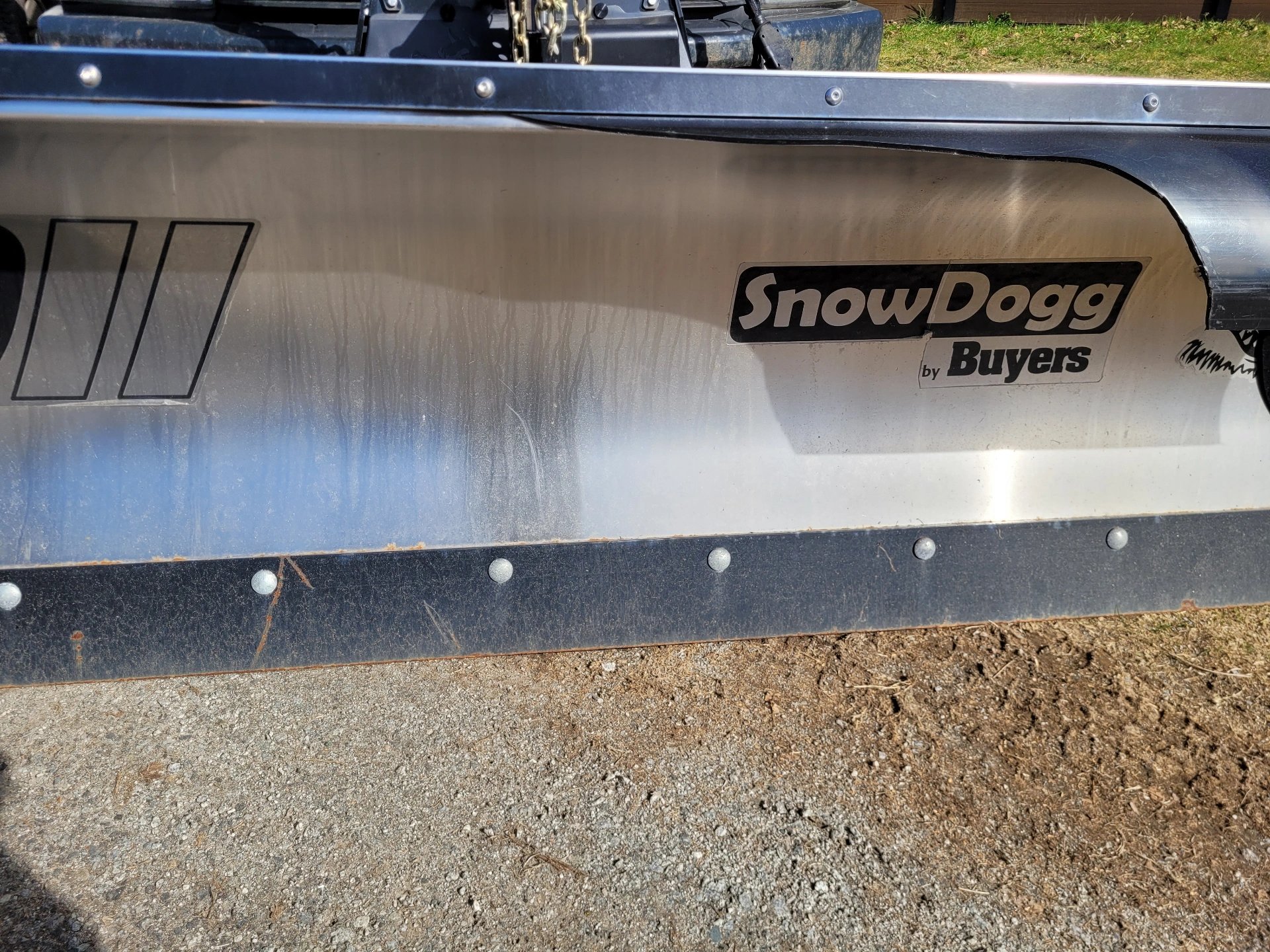 a close up picture of a silver SnowDogg plow blade