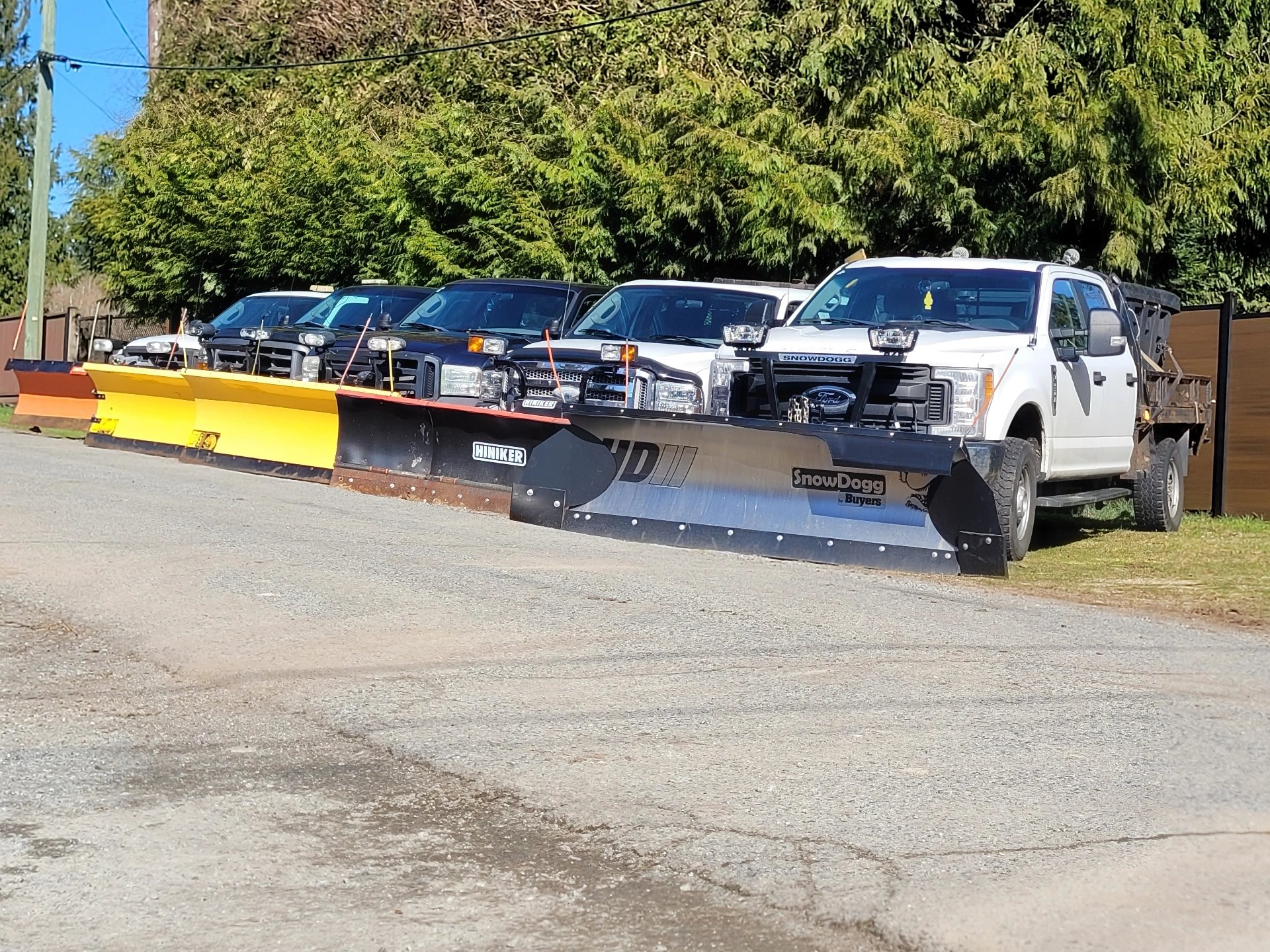 a picture of a street with 5 tucks with plows parked on angles facing the street