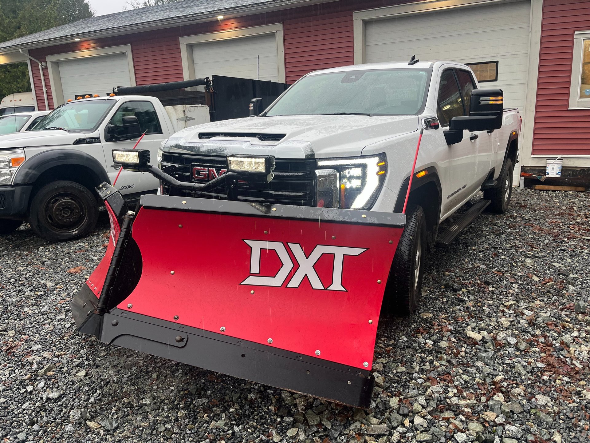 a white truck with a red DXT brand v plow on the front