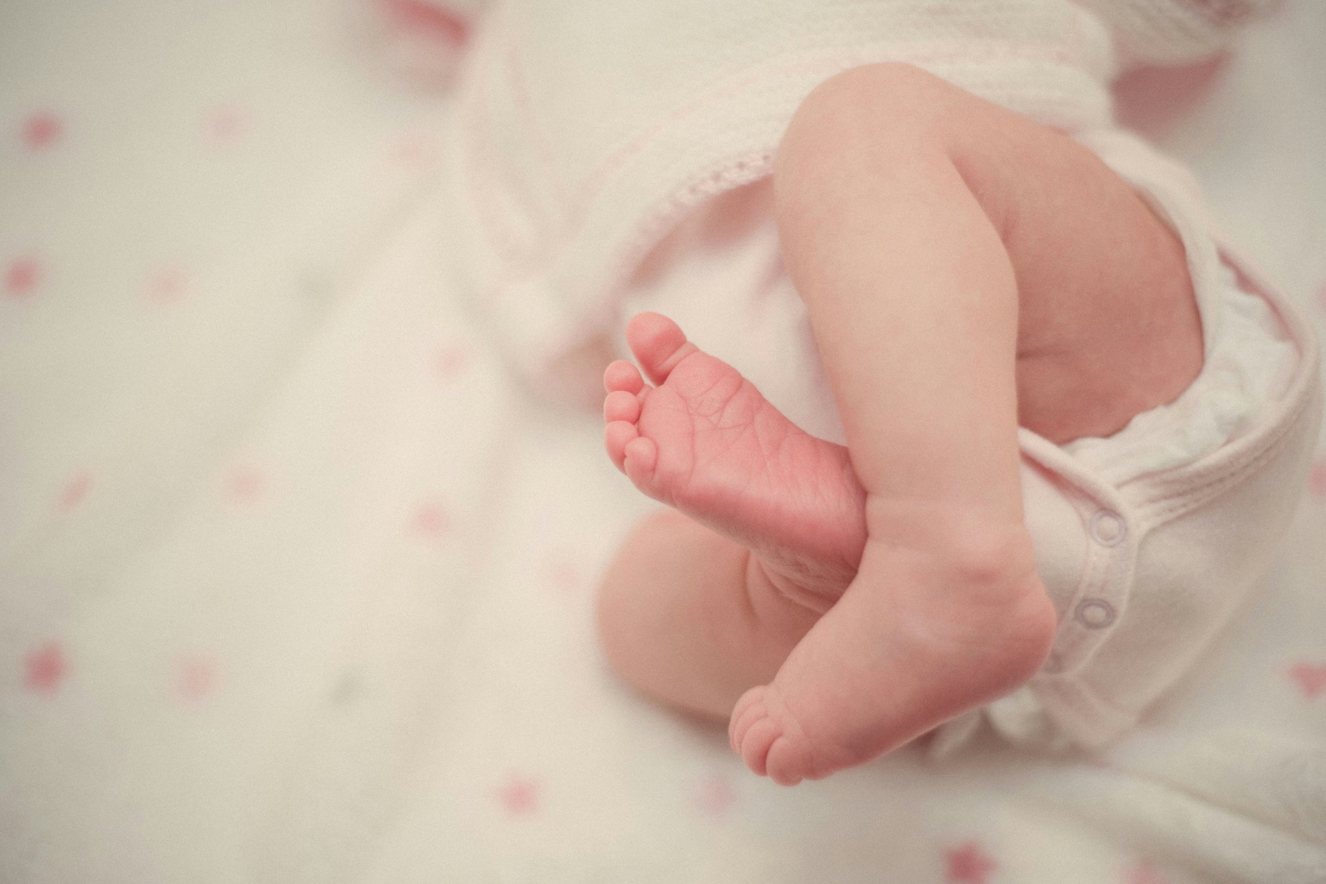barefooted baby covering white blanket