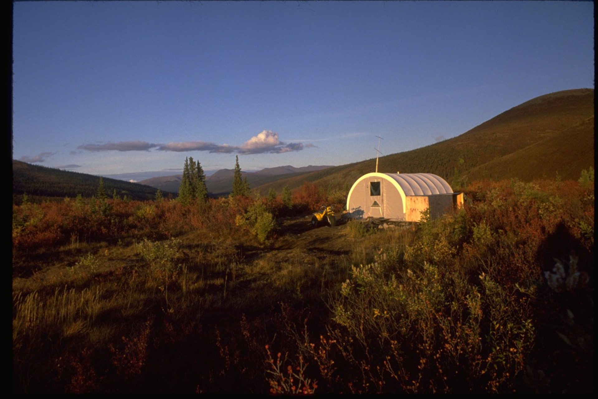 Alaska backcountry hunting camp featuring a white dome tent at sunset.