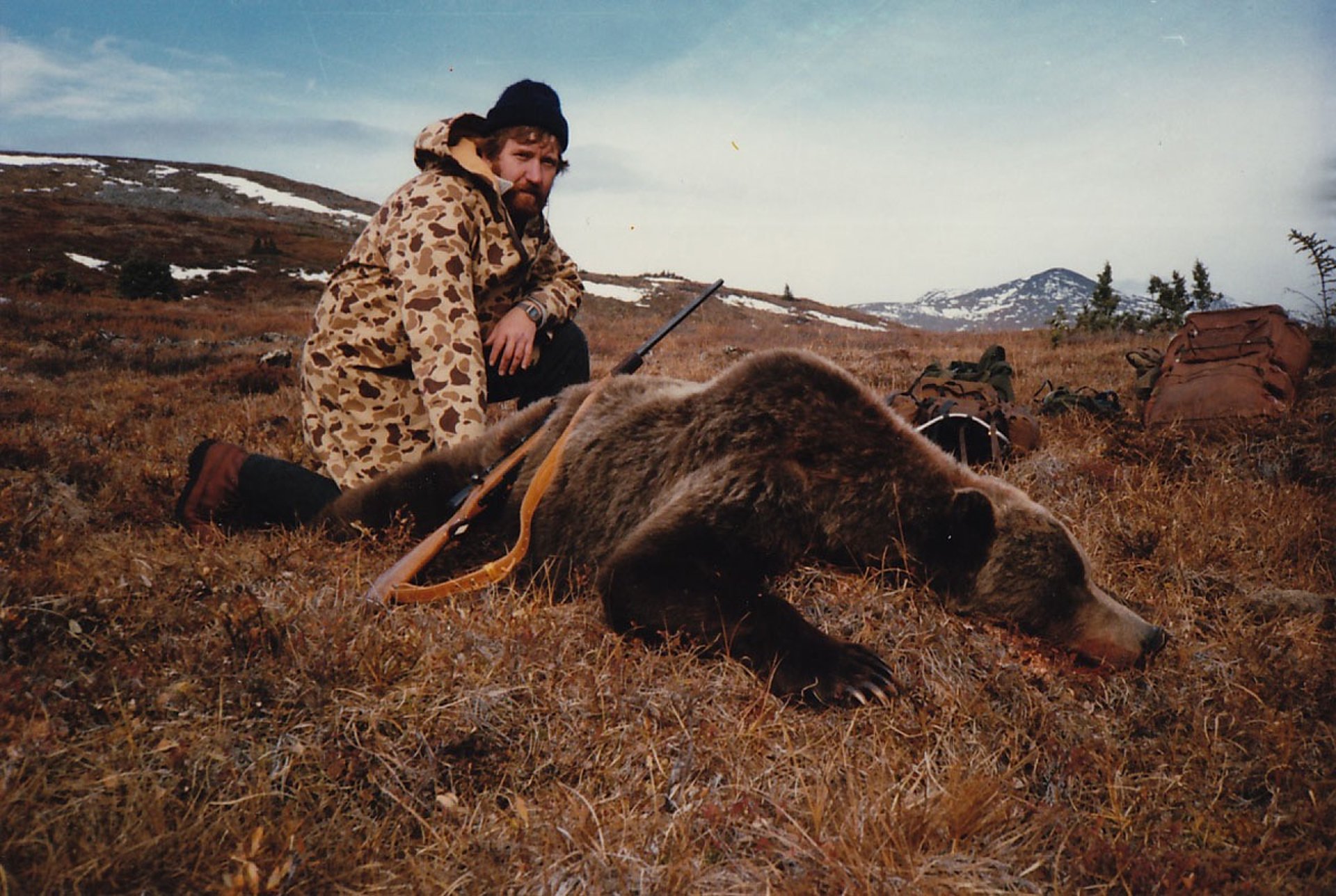 Hunter surveying the vast Alaskan mountain landscape during a big game hunt.