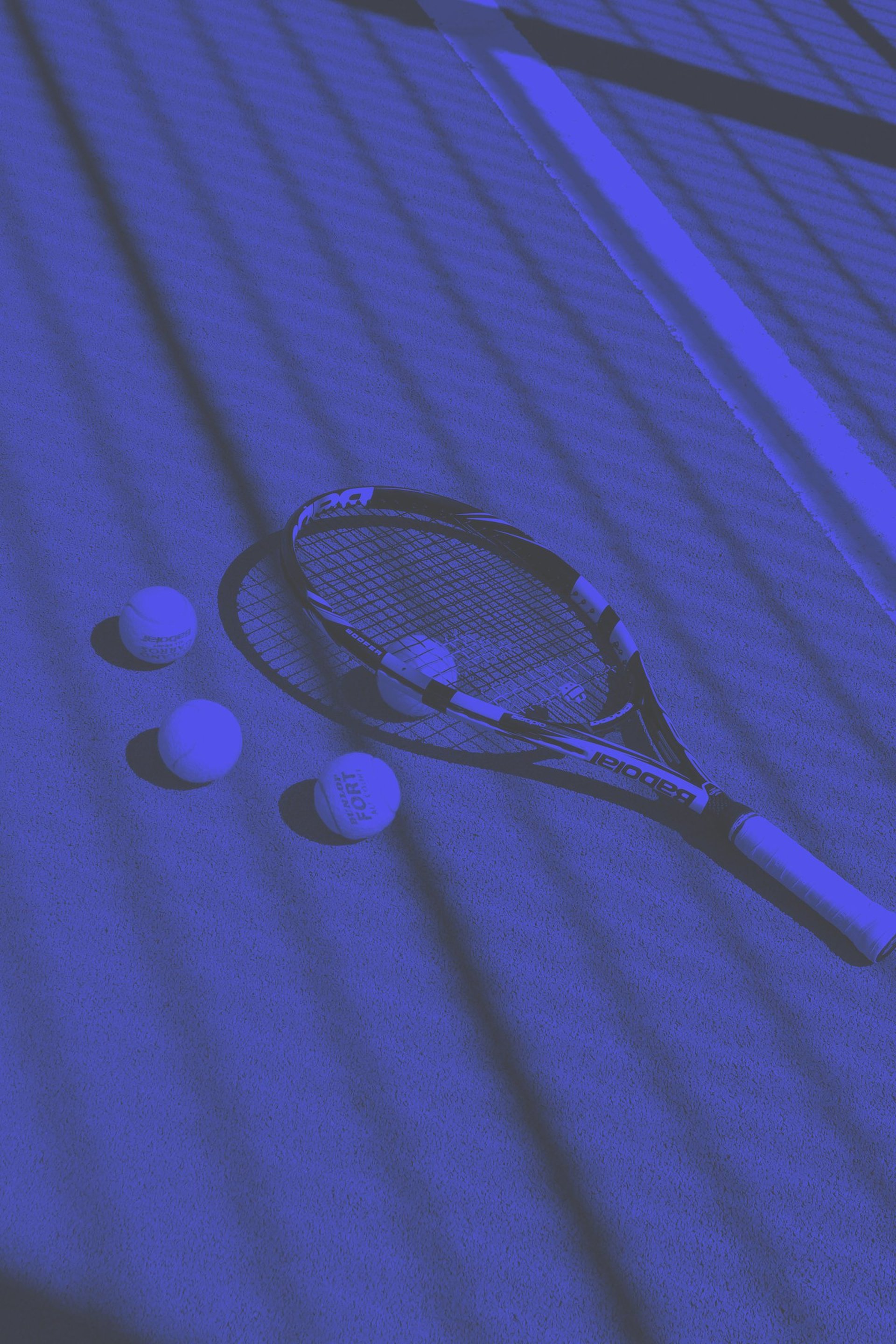 a tennis racket and four tennis balls on a court