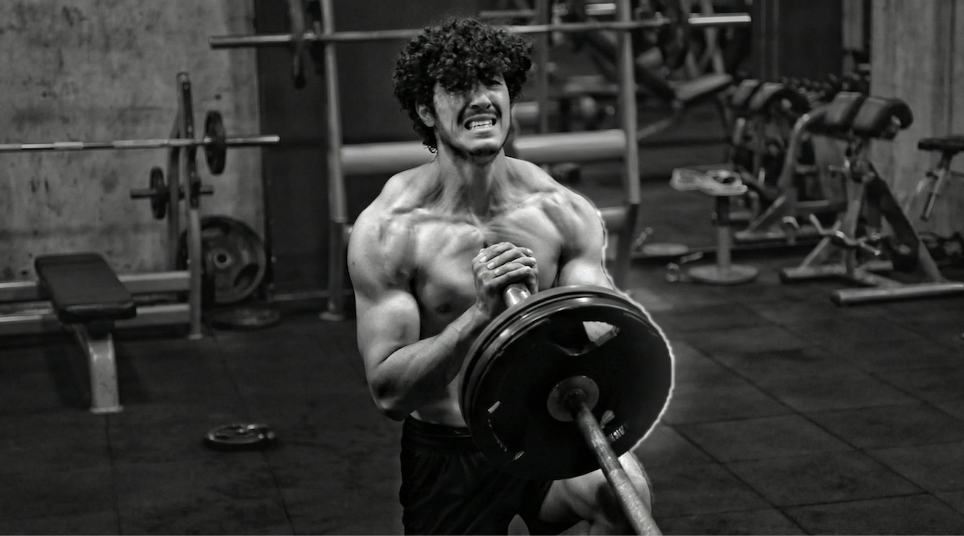 topless man in black shorts sitting on black and silver barbell